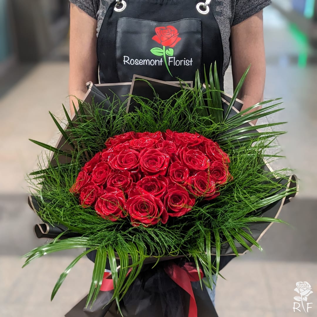 Two Dozen Long Stem Premium Roses - Luxury Wrapped Bouquet - 24 Long-stemmed premium red roses are hand-crafted by our skilled designer in a perfectly round bouquet with accenting greenery, packaged in our luxury black paper and ribbon.