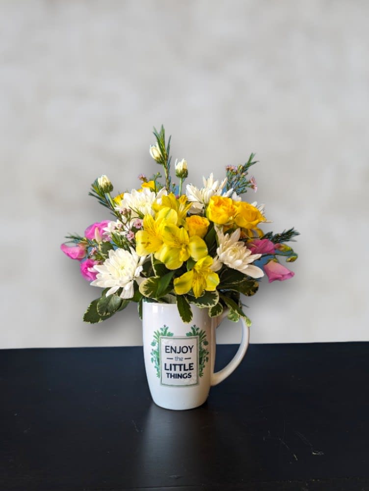 Cup O' Blossoms by Art & Flowers Cup O' Blossoms by Art & Flowers - Meet 'Cup O' Blossoms' – the delightful surprise that's sure to bring a smile. Nestled within a reusable ceramic mug, this petite floral arrangement is a joyful addition to any space. Perfect for gifting or brightening up your own day, 'Cup O' Blossoms' combines the beauty of nature with the warmth of a heartfelt gesture, guaranteed to bring a smile to someone's face. Mug styles and flowers will vary.