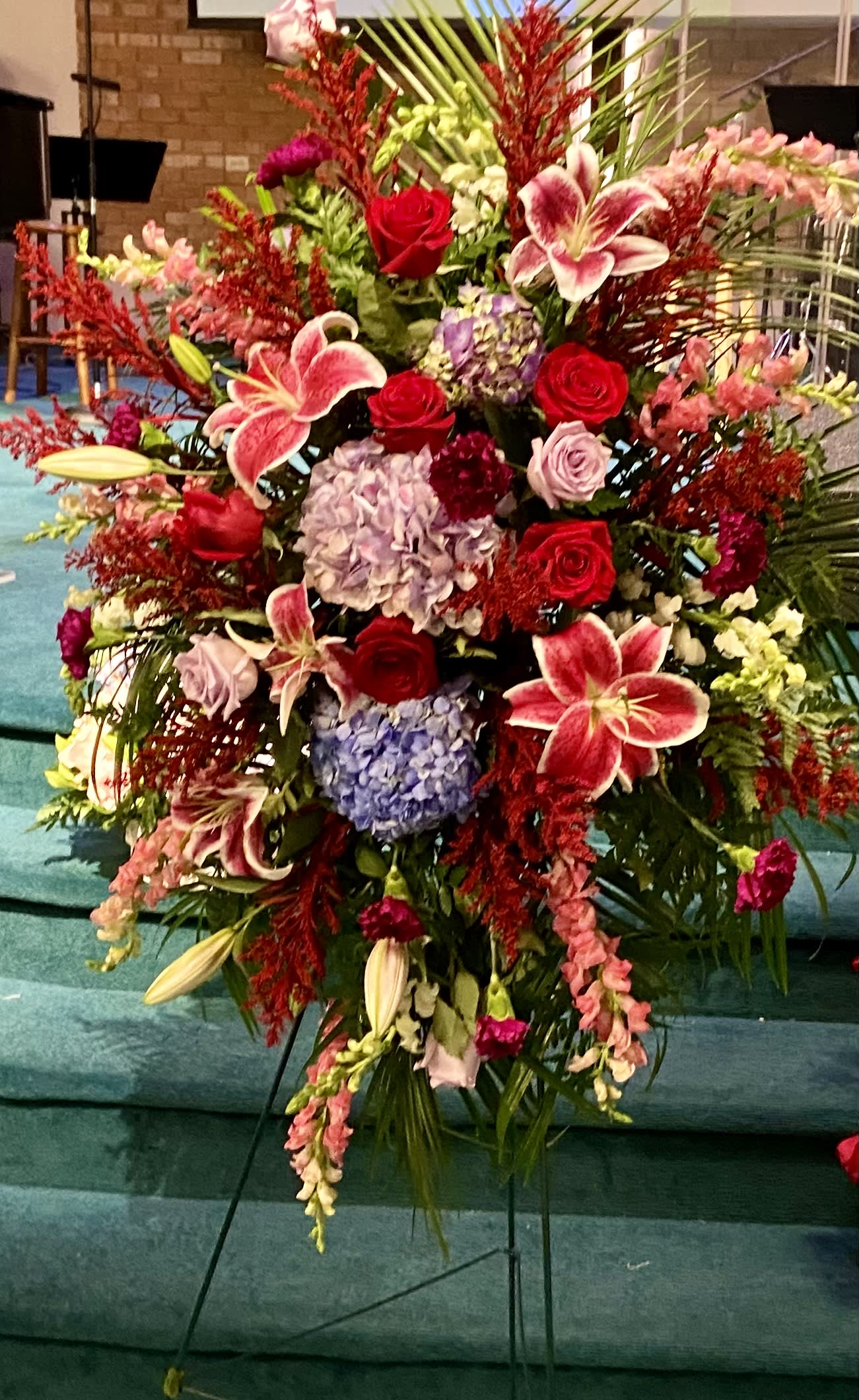 Ruby Standing Spray - Let this arrangement of ruby, purple and blue celebrate the life of your loved one.