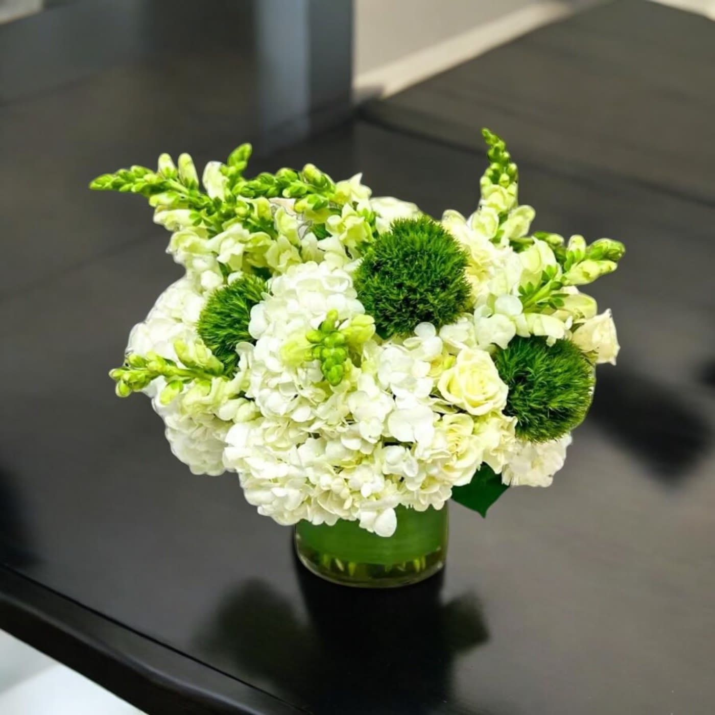 Emerald Medows - Cylinder vase displaying hydrangeas, snap, dragons, spray roses and green dianthus balls.