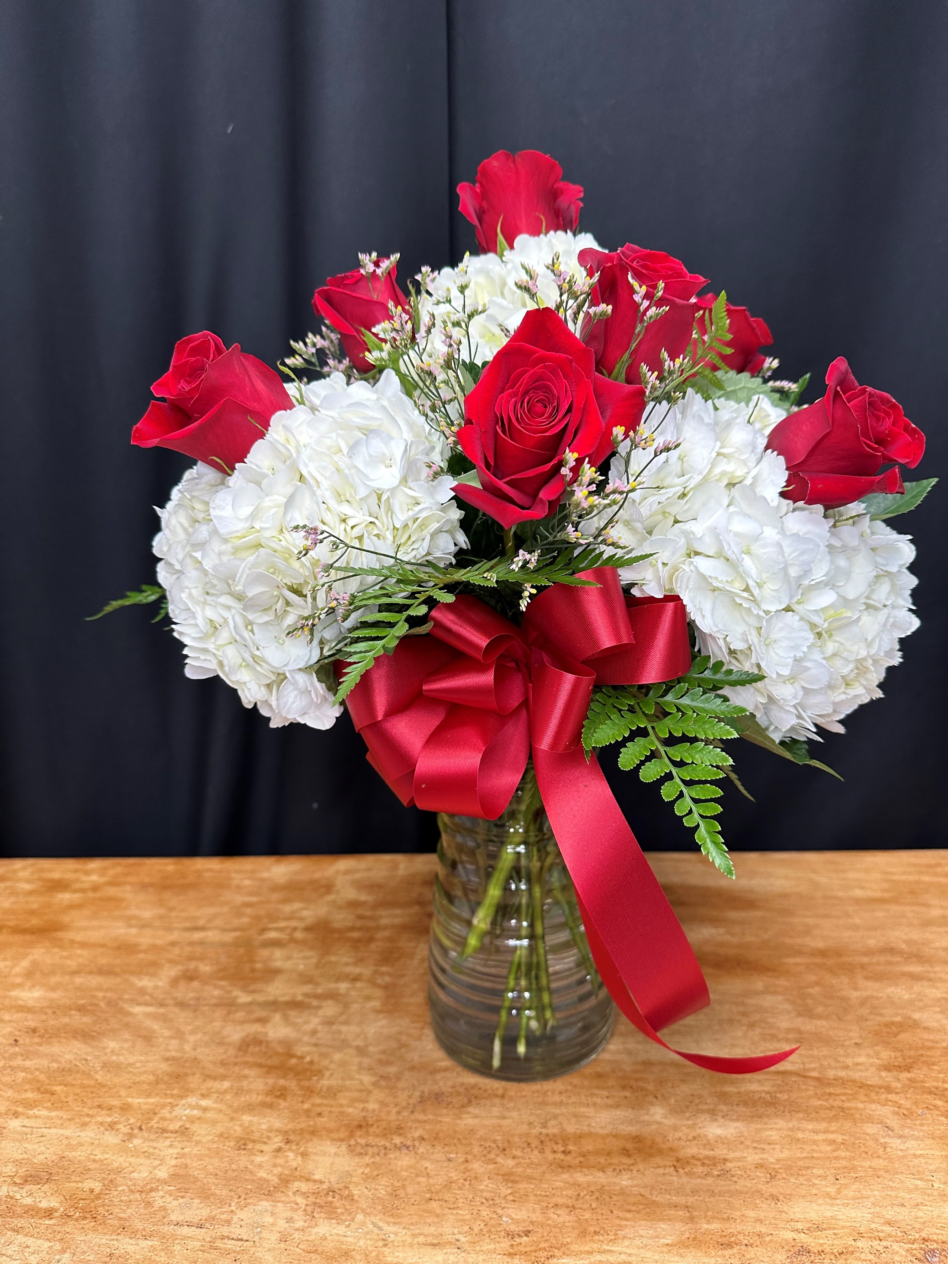 Blushing Beauty - Blushing Beauty, a stunning arrangement of one dozen red roses and soft white hydrangeas, perfect for any romantic occasion. This elegant pairing of passionate red and pure white blooms creates a timeless expression of love and beauty. Perfect as a thoughtful gift or a centerpiece, this arrangement adds a touch of sophistication to any space