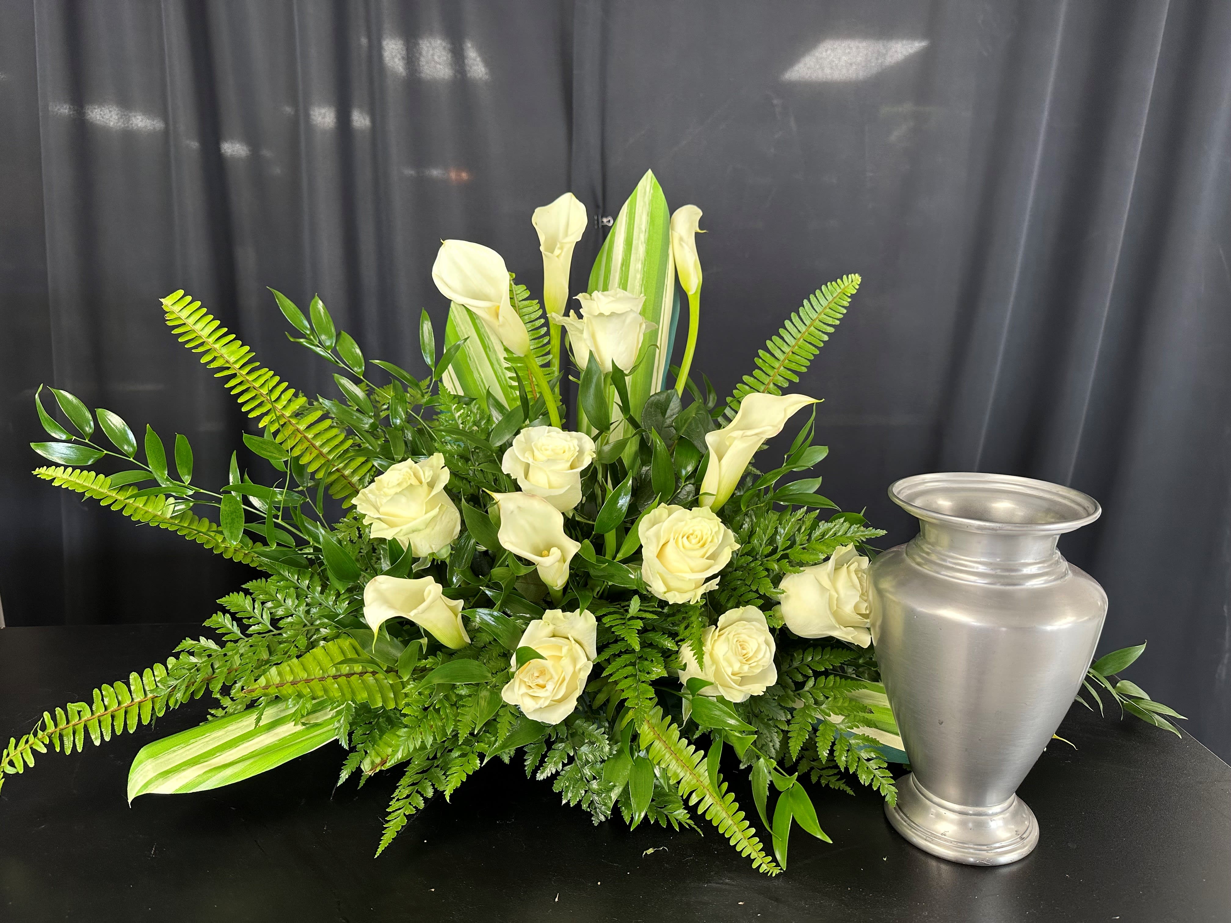 Calla Lily Comfort - The pristine beauty of white calla lilies and roses is showcased against a backdrop of lush greenery in this exquisite arrangement. Each bloom exudes elegance and purity, while the verdant foliage adds a touch of freshness and vibrancy. Whether adorning a special occasion or serving as a heartfelt expression of sympathy, this arrangement captures the essence of grace and sophistication, leaving a lasting impression on all who behold it.