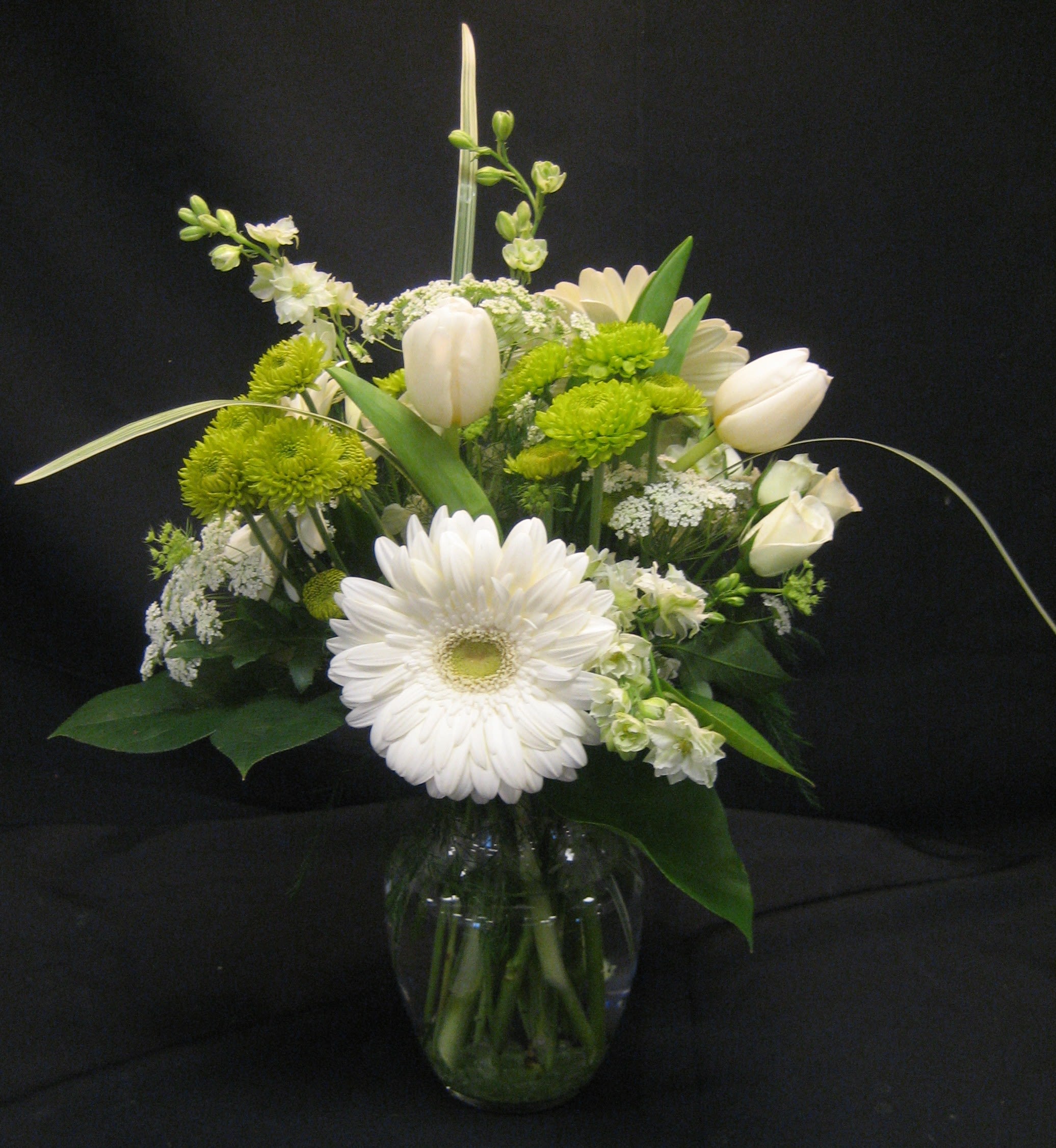 Serene Moments E-35 - You can't get much more serene than white and green. This vase is filled with delicate Queen Ann's Lace, Tulips, Larkspur and more. 