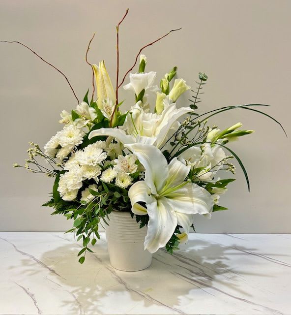 Pure Radiance  - Elegant and serene, Pure Radiance is an all-white floral arrangement that symbolizes grace, purity, and sophistication. Thoughtfully designed for sympathy, yet versatile enough for any occasion, this luminous display brings a sense of peace and refined beauty to any setting.