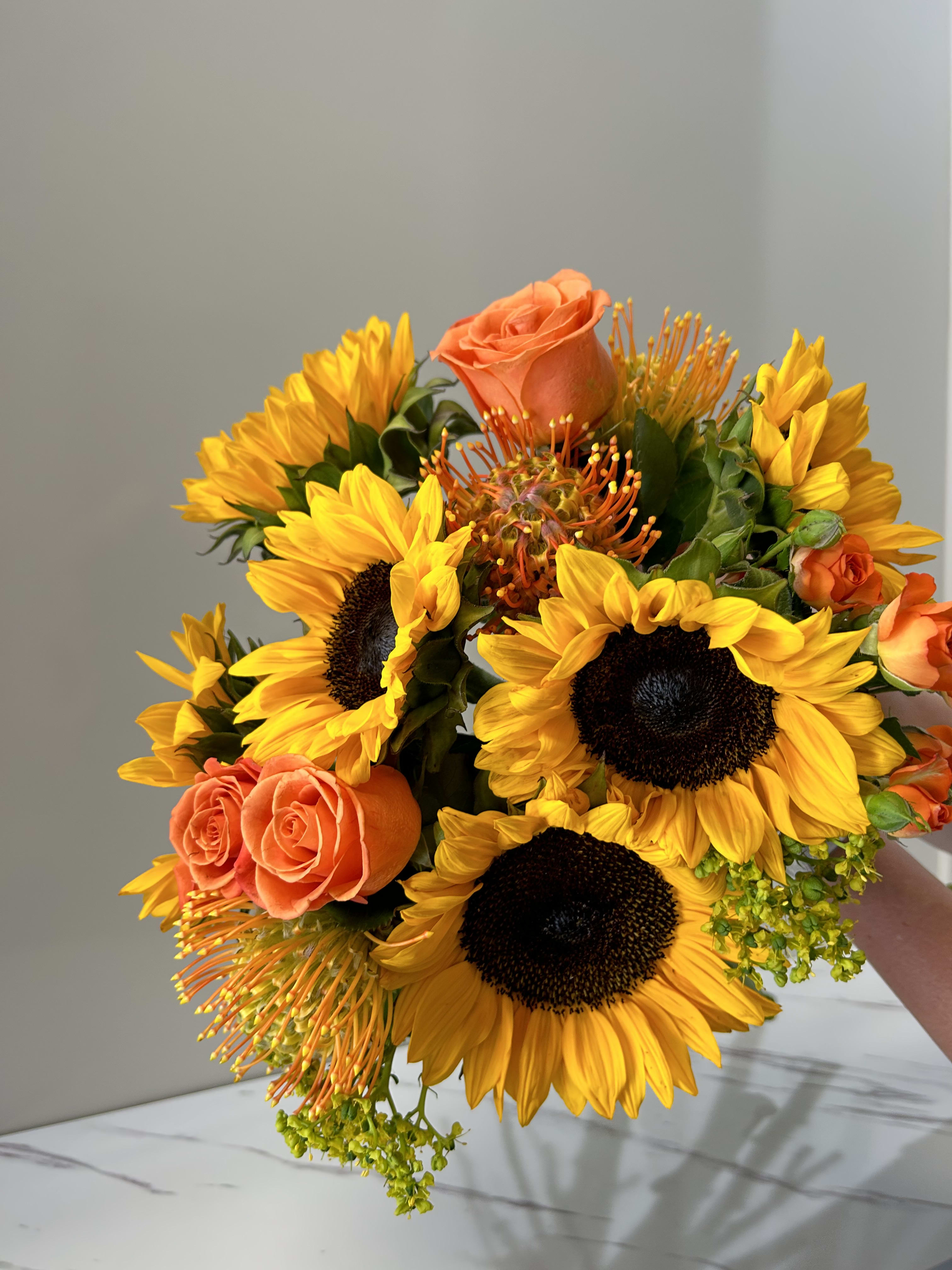 Sunflower Symphony- Seasonal Designer's Choice Sunflower Symphony- Seasonal Designer's Choice - A one-of-a-kind Floral arrangement will be created by our expert Designers that exudes elegance and sophistication. This stunning bouquet features radiant sunflowers and OTHER seasonal blooms, all artfully arranged in a beautiful vase. With its perfect balance of colors and textures, the "Sunflower Symphony" is an exquisite expression of love, gratitude, or admiration.