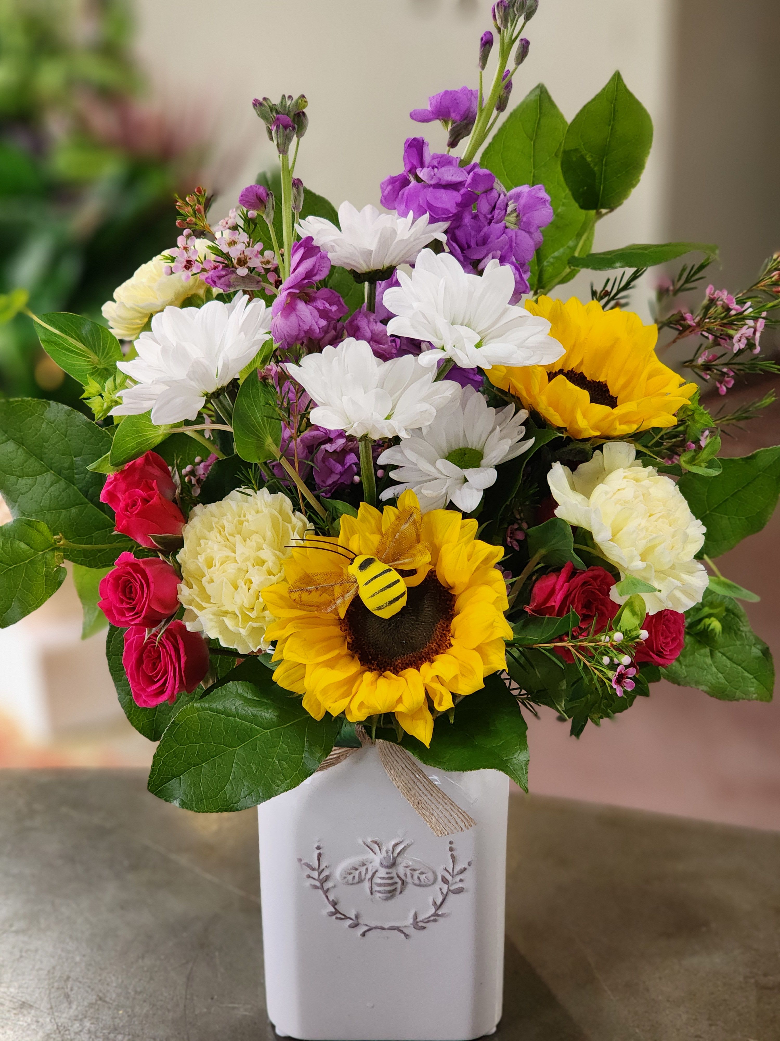 Sweet as Honey Bee Sweet as Honey Bee - Classic white ceramic jar style keepsake vase filled with white daisy's, fragrant stock, carnations, spray roses, greenery completes the arrangement.
