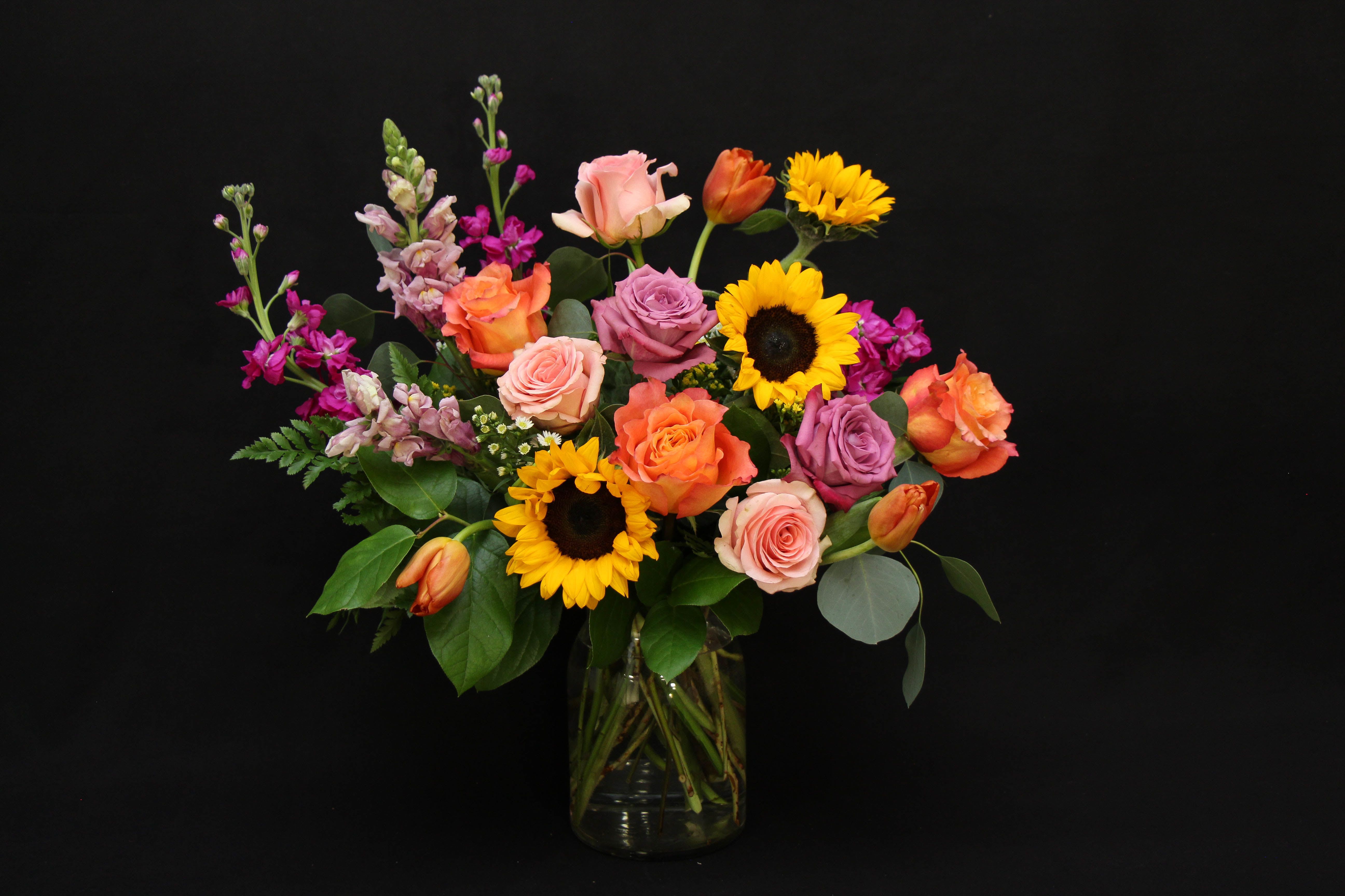 Crazy Little Thing  - This striking arrangement of pink, orange and purple in a clear vase will leave them beaming with joy.