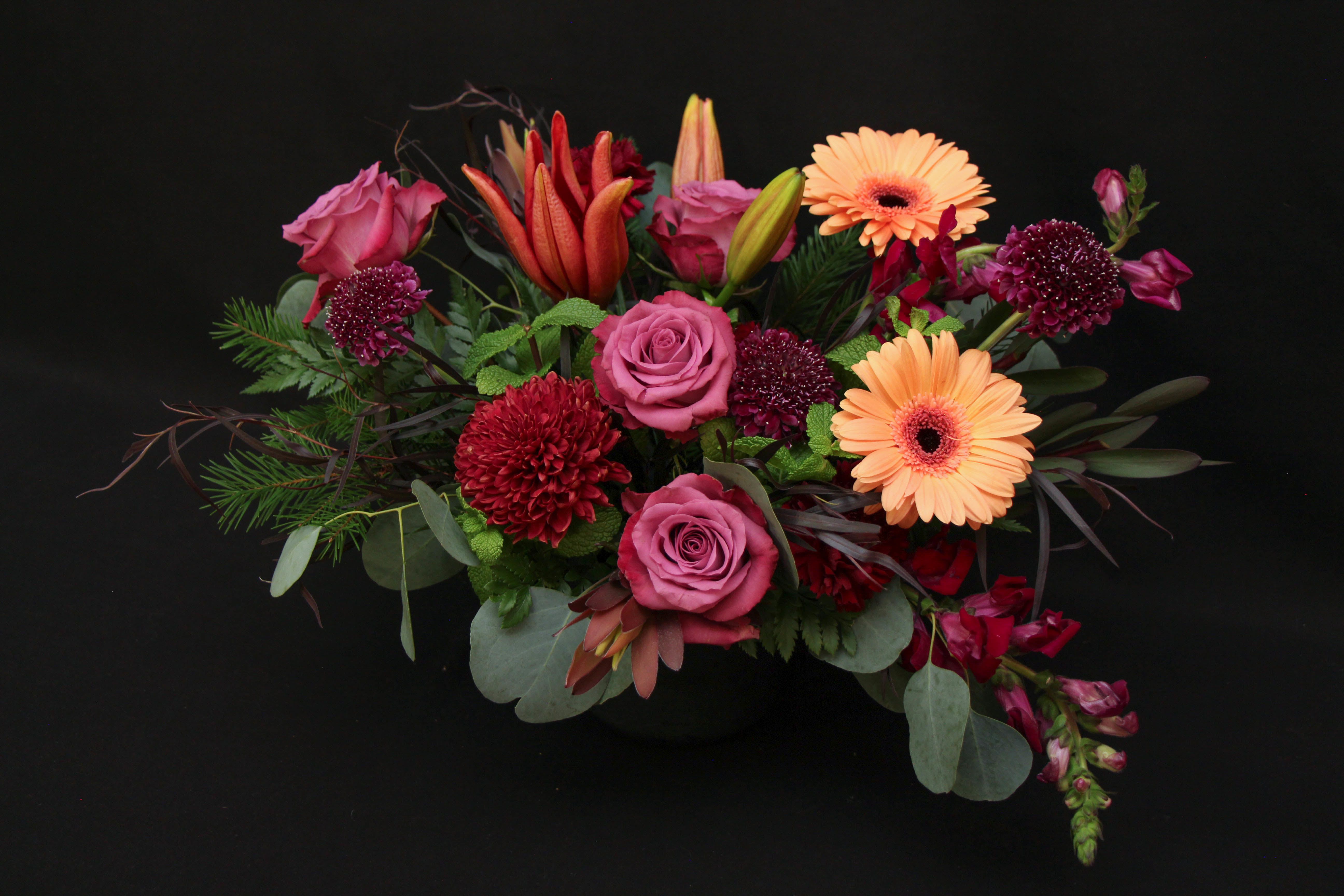 Full Moon - This beauty is a favorite in house. It's dark textures with a light pop of peach is just enough to put a smile on anyone's face. Our designer will pick the perfect vase to complete this arrangement.      