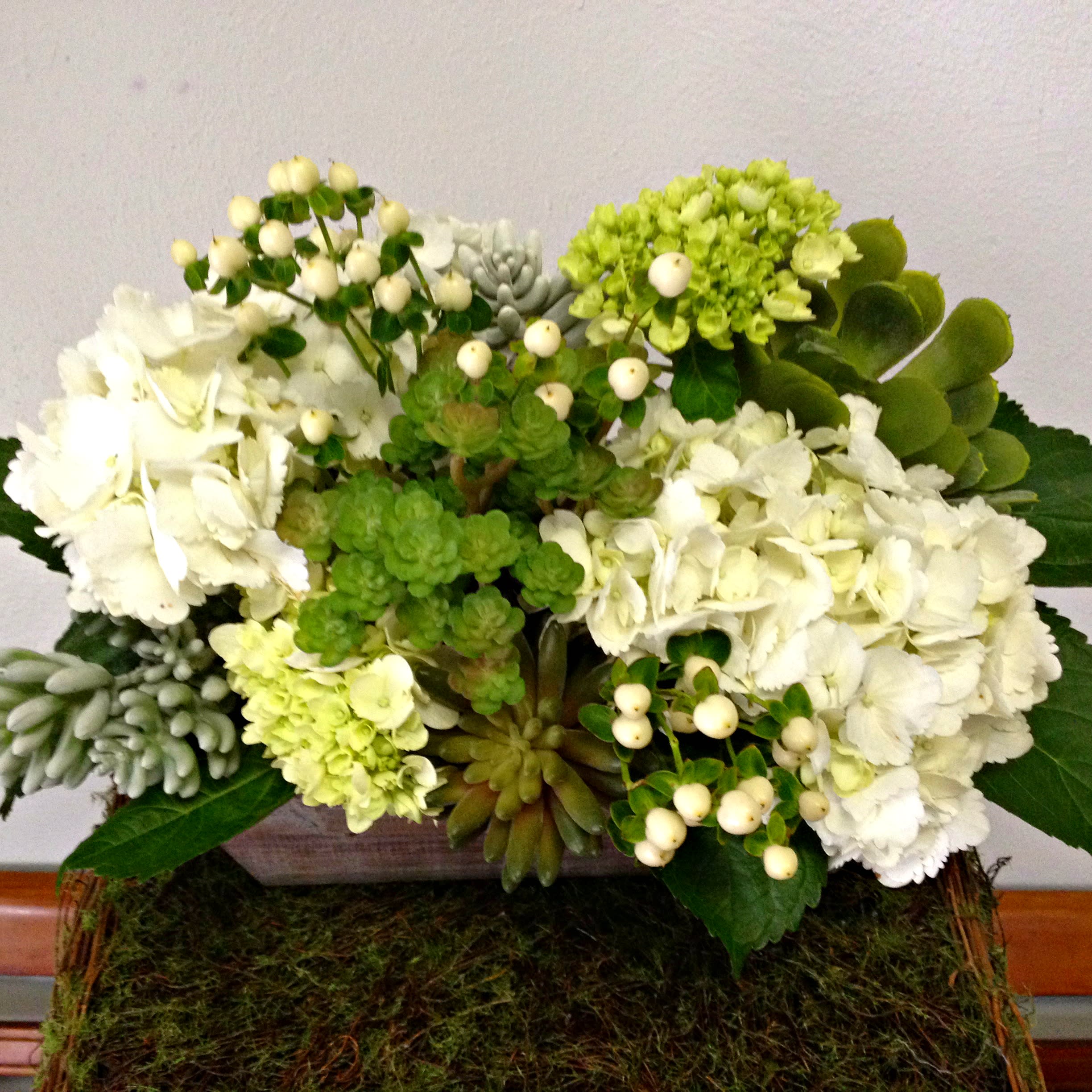 Woodland Wonder - Wonder what is real and what is not? Can you tell? Neither will they when this outdoor naturalistic design arrives. Faux succulent plants meticulously arranged with fresh green and white hydrangeas and St John's wort. Designed in a wooden trough planter. FAE-156
