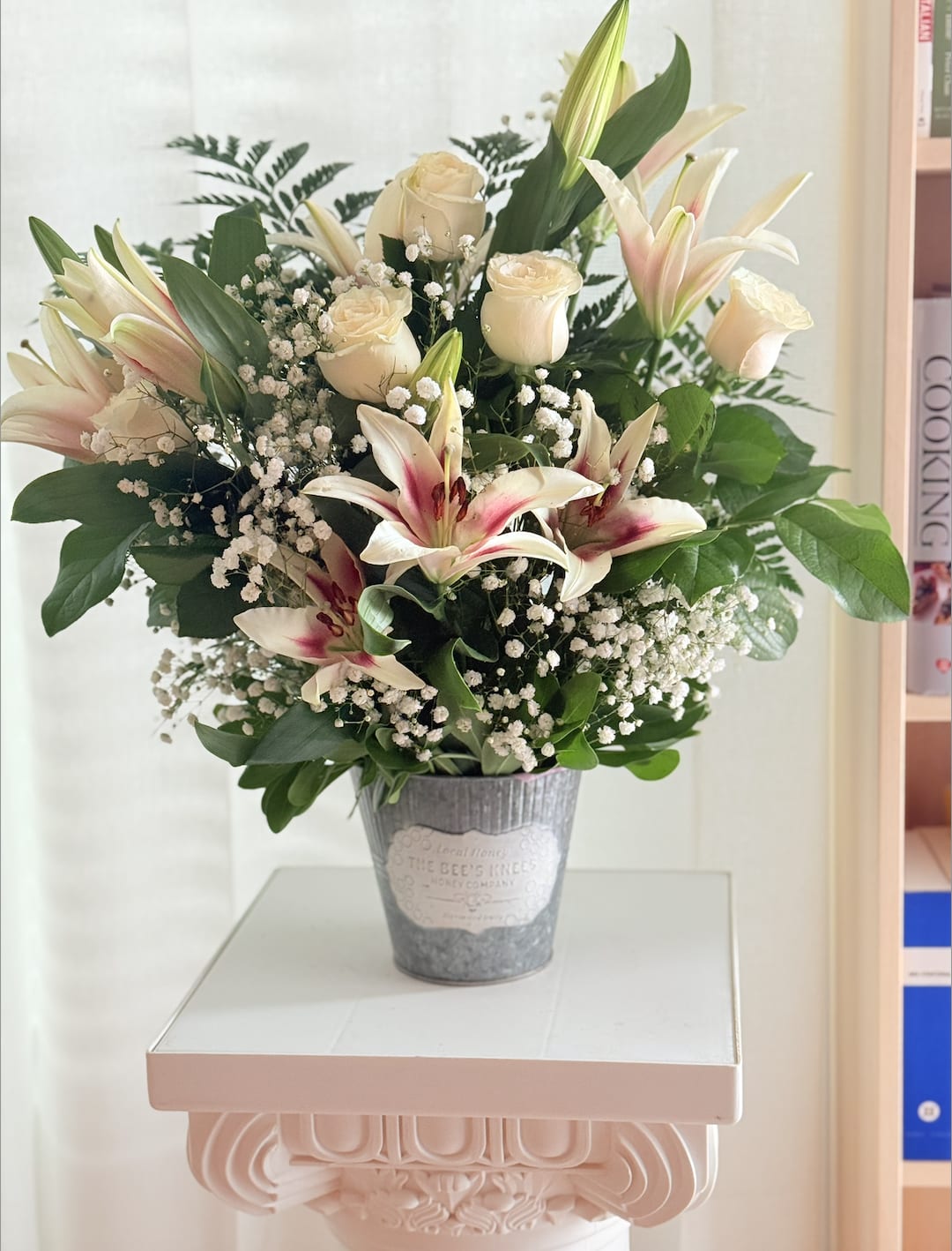 Elegant Embrace - Celebrate love, gratitude, or simply brighten someone’s day with our *Elegant Embrace* arrangement. This lush bouquet features creamy white roses, soft blush-pink lilies with striking burgundy centers, delicate baby's breath, and rich greenery—all thoughtfully arranged in a vintage-style galvanized tin vase. Perfect for Mother’s Day, anniversaries, or as a timeless gift of elegance.   *Includes:*  * White Roses * Pink Stargazer Lilies * Baby's Breath (Gypsophila) * Assorted Seasonal Greenery * Rustic Tin Vase (reusable)   *Approximate size:* 18–20&quot; H x 14–16&quot; W  *Availability:* Local delivery and pick up in Orlando, FL  A stunning and graceful floral gesture that speaks volumes without saying a word.* 