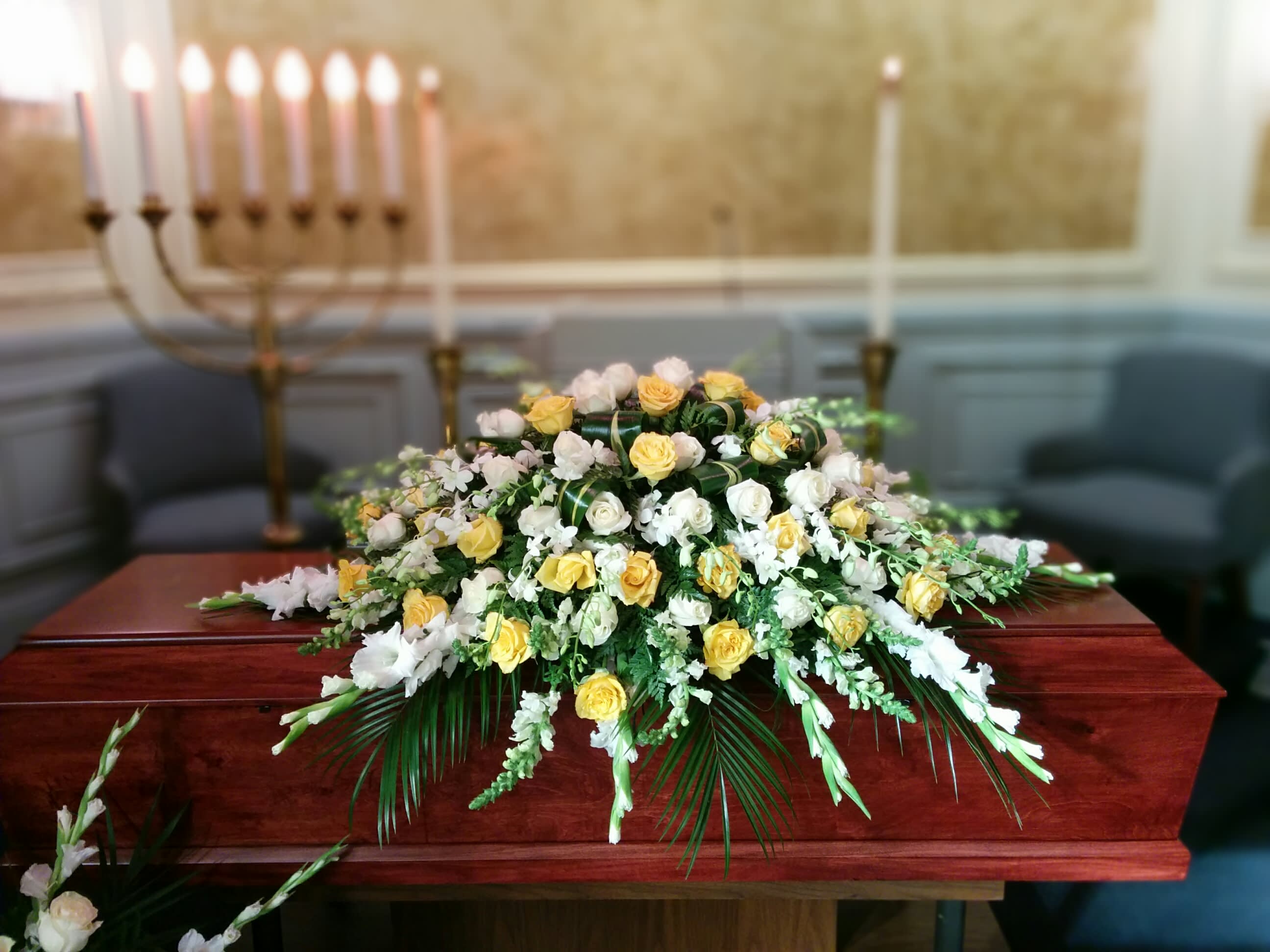 Loving Memory Casket Spray - Loving Memory Casket Spray includes: Yellow Roses White Carnations White Gladiolus White Dendrobium Orchids This type of design usually measures approximately 5 ft x 3 ft x 1ft and is meant for funeral services ONLY. This design includes a free banner (please include a banner sign in the Special Instruction Box or Message Box with the title “BANNER”).  In the event a banner space is left blank for any reason, ONLY a card message will be included. Banners are printed in a black 2.5-inch wide ribbon with silver ink. Currently, we don't offer any other colors. If the service is the same day as the order was placed we cannot guarantee delivery by a certain time. And flowers will be delivered during normal business hours.  To ensure the delivered flowers match the displayed photo as close as possible we recommend ordering 3-5 days in advance. For the same or next day deliveries, we reserve a right to substitute flowers with the same or greater value. Please read our substitution policies below.