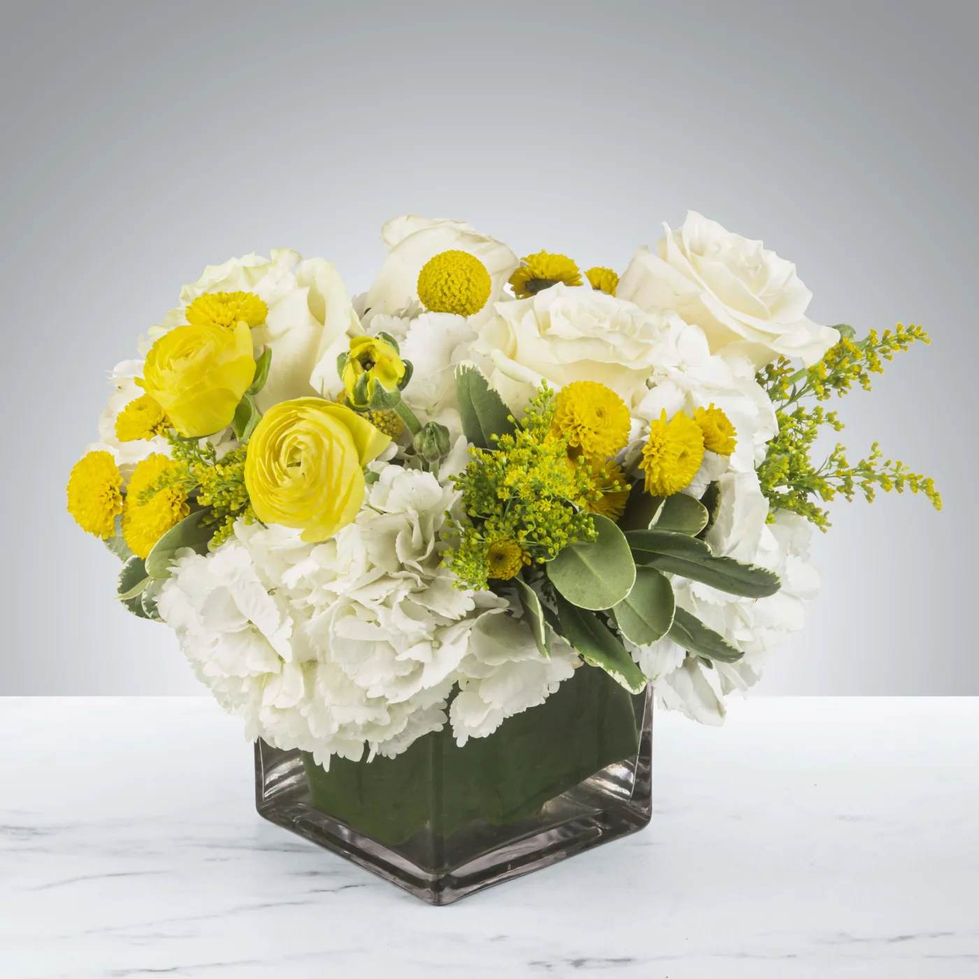 Honeybee by BloomNation™ Honeybee by BloomNation™ - This white and yellow arrangement includes cream roses, button mums, and ranunculuses. Honeybee by BloomNation™ is the perfect way to brighten a day! Send a little joy and make somebody feel good. Perfect to send as a get well soon present or just because! APPROXIMATE DIMENSIONS 12" W X 12" H