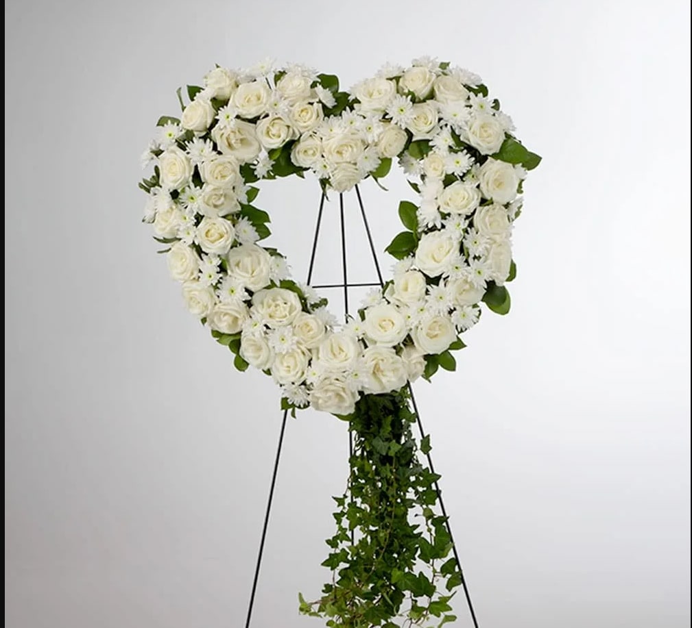 Love in our Hearts by BloomNation™ Love in our Hearts by BloomNation™ - An all white tribute, this heart shaped easel shows your everlasting love. Featuring a variety of white flowers and greenery, this heart with a trail of ivy compliments the beauty of life.