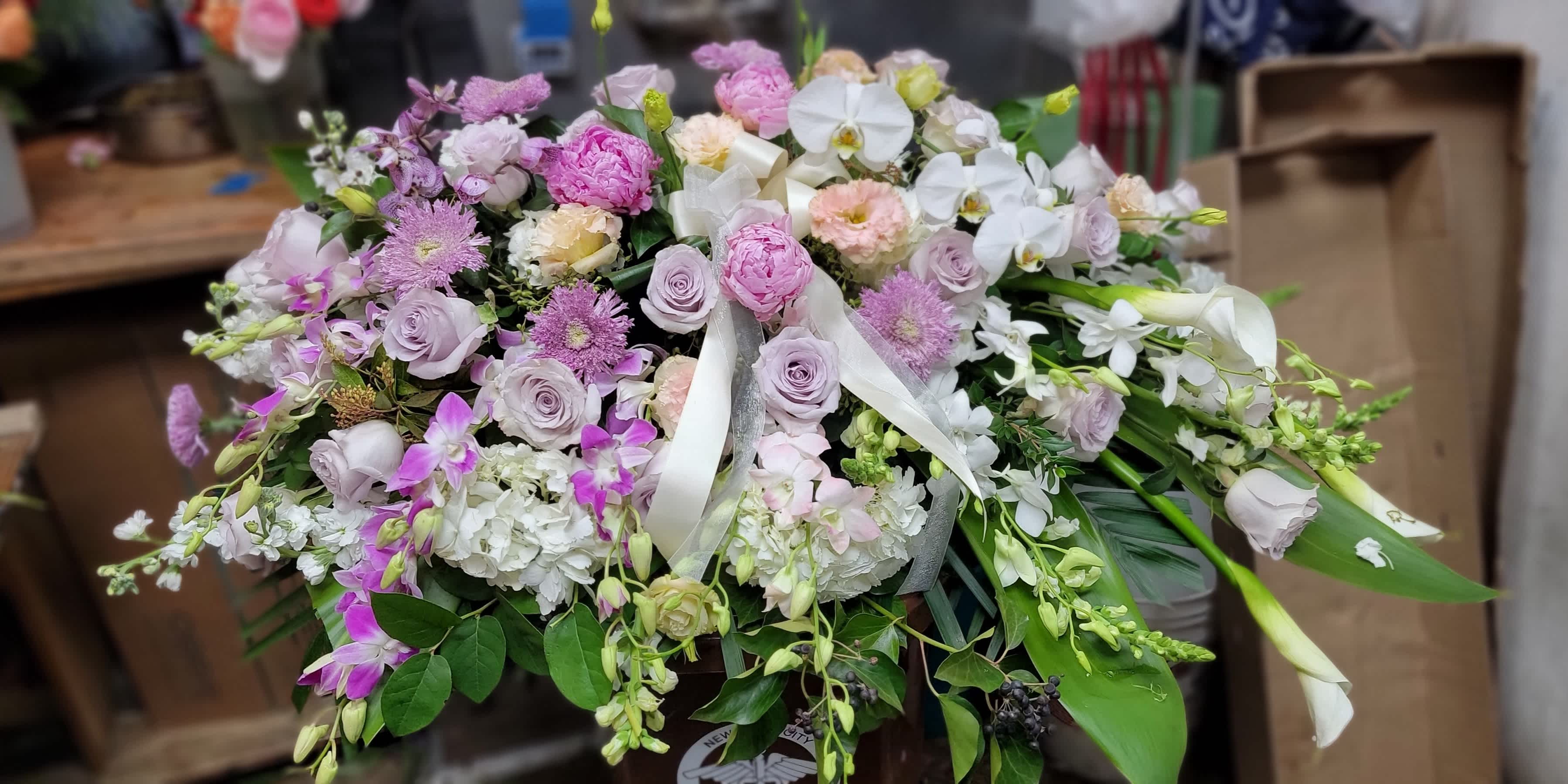 Memories Casket Spray Memories Casket Spray - white calla lilies, pink roses, pink peony, pink stargazer lilies, pink carnations, pink larkspur, pink snapdragons, white stock, white phalaenopsis orchid, green ivy, sword fern, silver dollar eucalyptus, seeded eucalyptus, and lemon leaf.