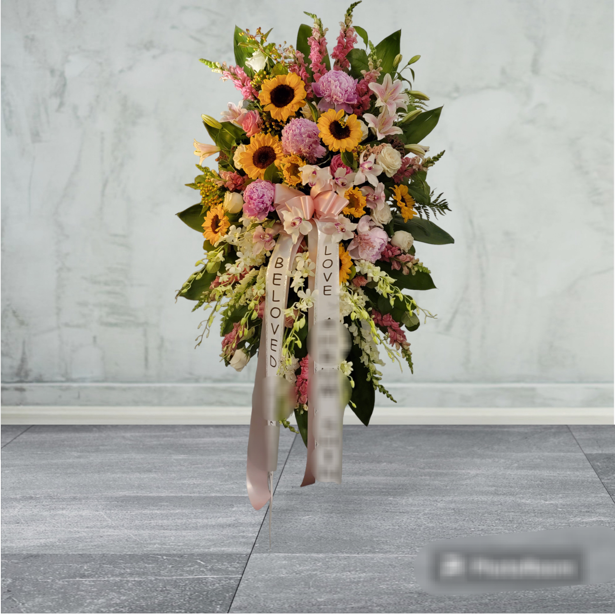 Sweet Memory Spray Sweet Memory Spray - This spray features hot pink snap, pink Asiatic lilies, green carnations, medium yellow sunflowers, bupleurum, myrtle, sword fern, silver dollar eucalyptus, and lemon leaf. Delivered on a wire easel. white dendrobium orchid.