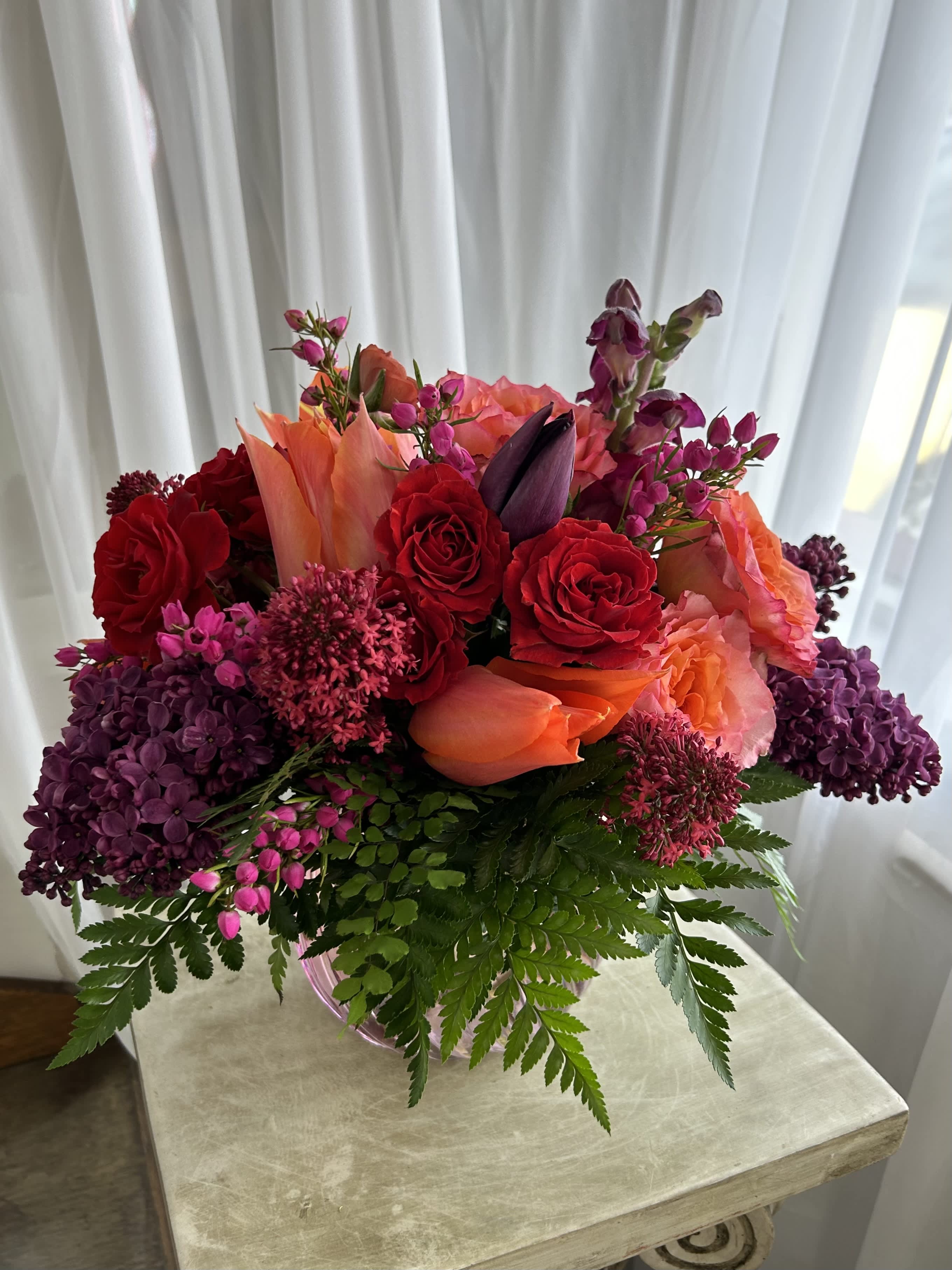 Hawaiian Punch Hawaiian Punch - A bright mix of magenta, pink, reds, and oranges inside of a purple and coral vase. This design features flowers such as roses, lilac, tulips, and boronia. It is perfect as a centerpiece or as a gift. As always, this design is subject to substitution based on what is available.