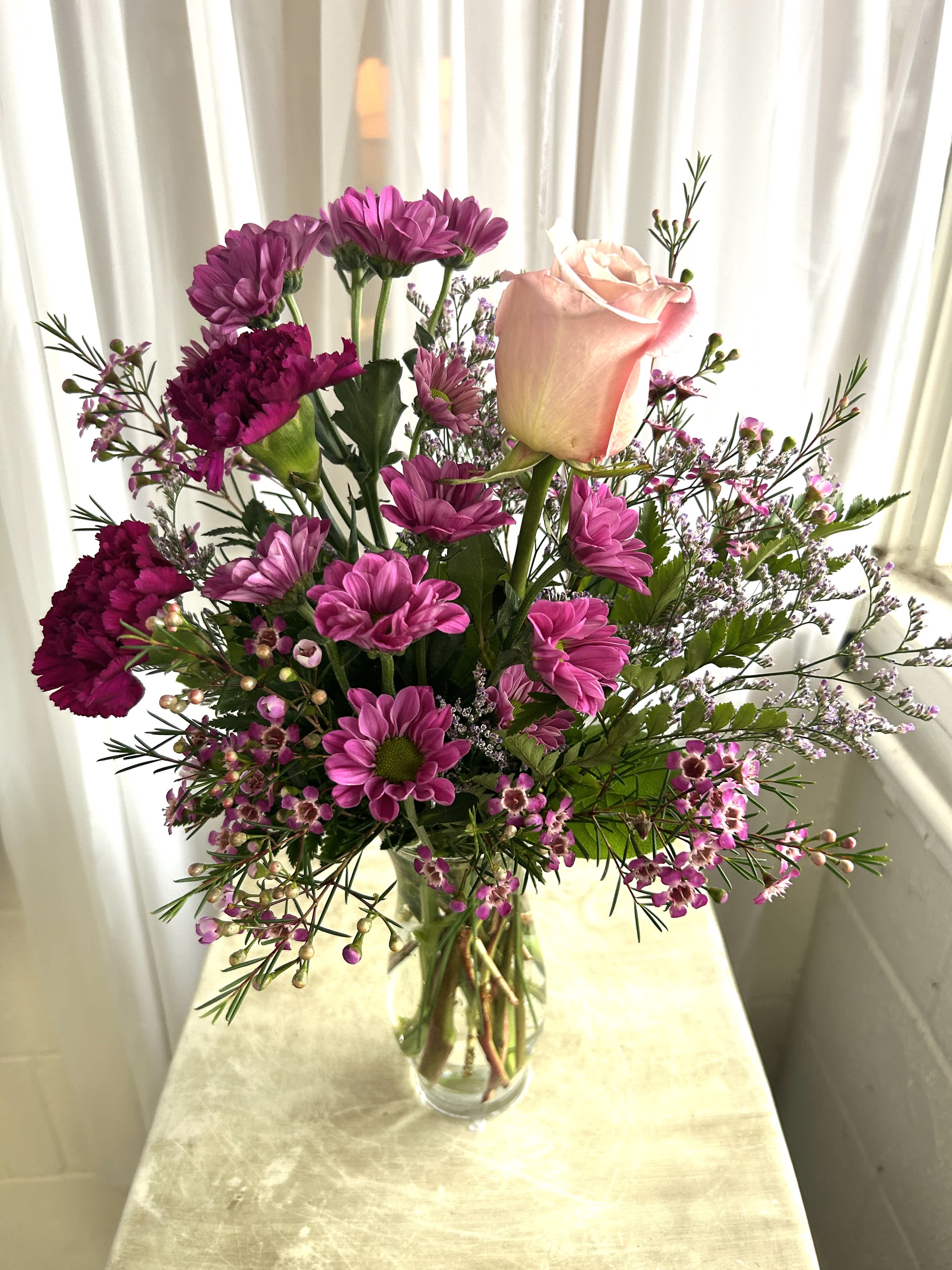 Kiss On The Cheek - A cute and affordable option for your sweetheart featuring carnations, roses, mums and caspia. As always, flowers are subject to substitution based on what we have in stock. 