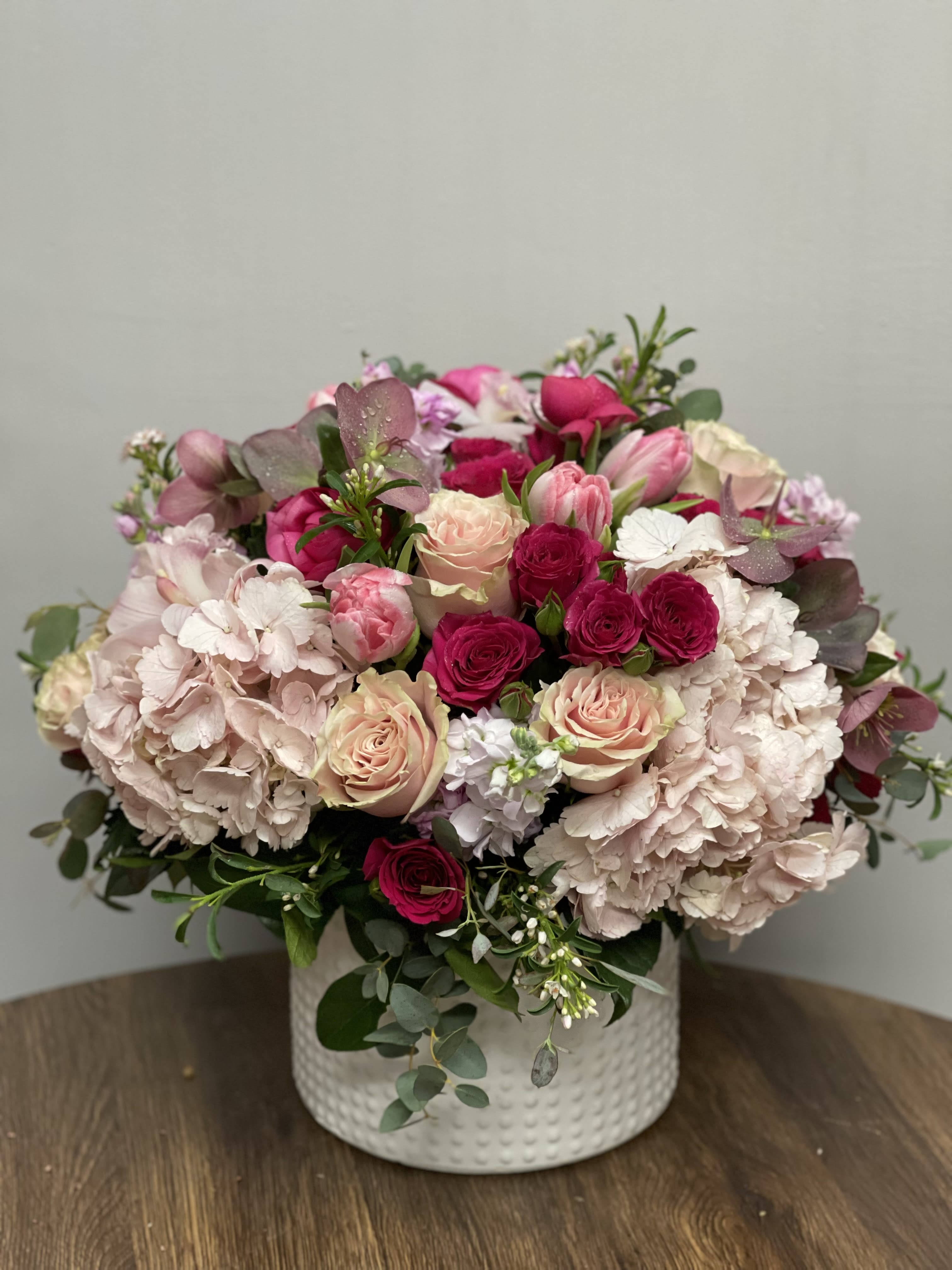 Pretty in Pink - Flower arrangement in white ceramic container with beautiful combination of light pink Hydrangeas, Roses, Tulips, Stock, Ranunculus and other seasonal flowers in lighter and darker shades of pink subject to seasonal availability. 