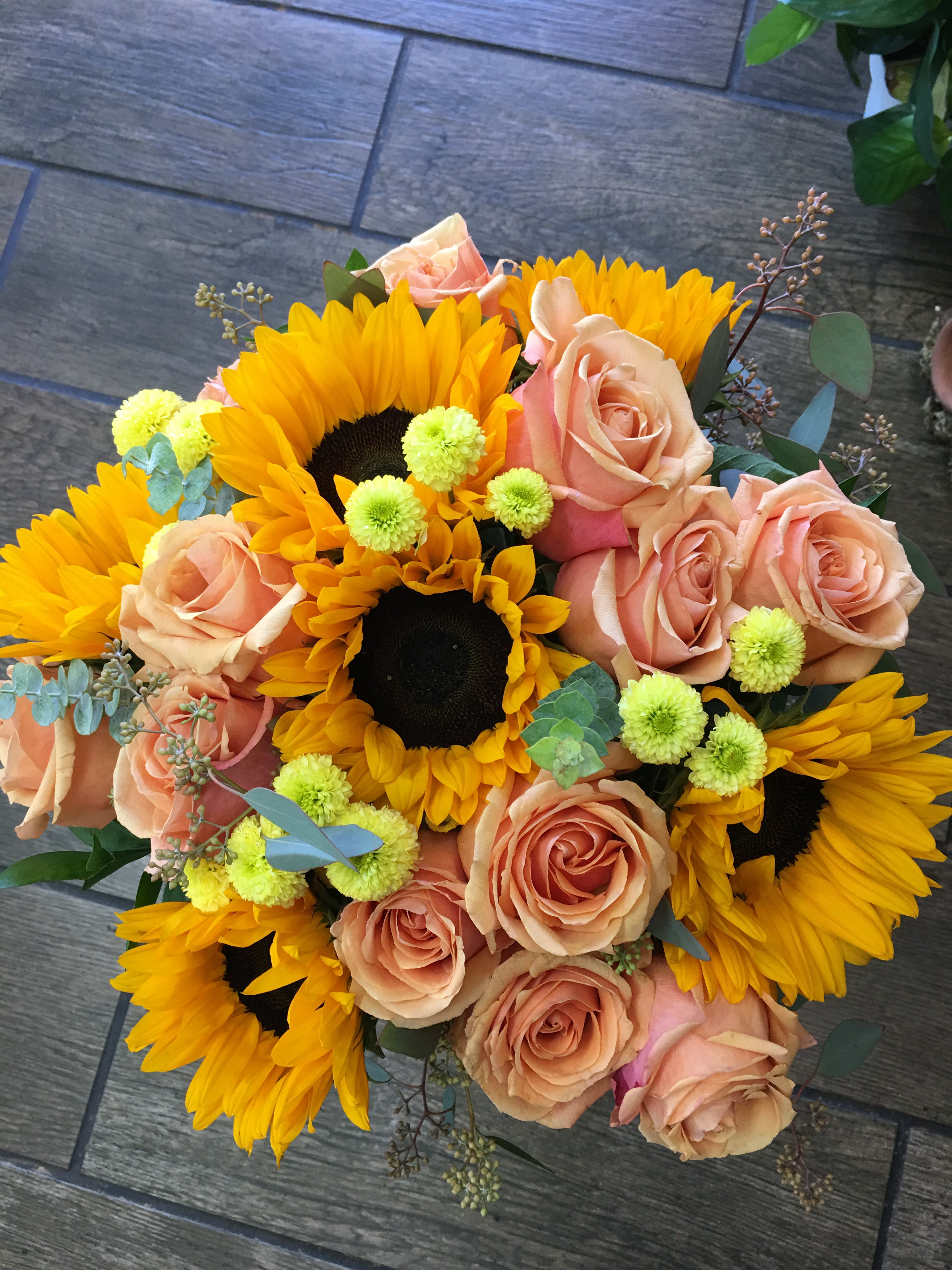 Peach Sunshine  - Hand tide bouquet May consist of peach roses sunflowers, yellow pompom, foliage wrap in mesh, burlap, or cellophane 
