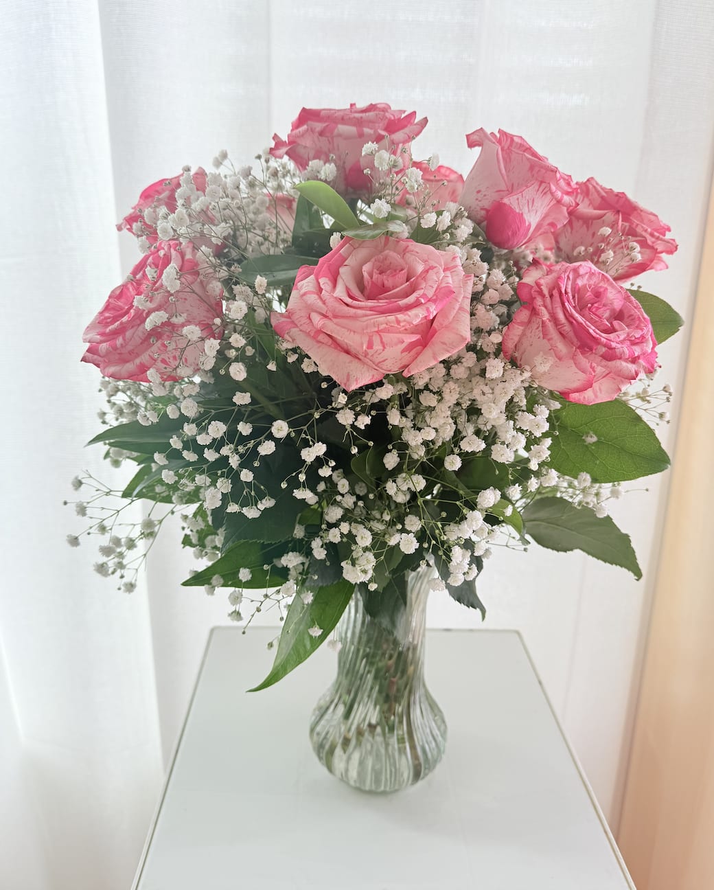 Cotton Candy Roses - Sweet, soft, and full of charm — *Cotton Candy Roses* features pink-and-white variegated roses paired beautifully with delicate baby’s breath and fresh greenery. Presented in a graceful glass vase, this bouquet is the perfect way to say “I’m thinking of you,” “Congratulations,” or simply “You’re loved.” A romantic and elegant gift that feels as light and joyful as cotton candy.   Dulce, suave y encantador — *Cotton Candy Roses* presenta rosas bicolor en tonos rosa y blanco, acompañadas de elegantes flores de nube y follaje fresco. Colocado en un jarrón de cristal delicado, este arreglo es ideal para decir “Estoy pensando en ti”, “Felicidades” o simplemente “Te quiero”. Un detalle romántico y elegante que transmite ternura al instante. 