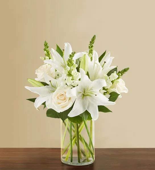 Classic All White Arrangement™ for Sympathy - White flowers have a timelessness and elegance that brings comfort during life’s difficult moments. Hand-gathered by our caring florists with touches of lush greenery, this classic arrangement beautifully conveys your heartfelt condolences. All-around arrangement with white roses, lilies and snapdragons; accented with assorted greenery Artistically designed in a glass cylinder vase; measures 8&quot;H Large arrangement measures approximately 20&quot;H x 20&quot;W Medium arrangement measures approximately 19&quot;H x 16&quot;W Small arrangement measures approximately 18&quot;H x 14&quot;W Our florists hand-design each arrangement, so varieties and container may vary due to local availability To ensure lasting beauty, lilies may arrive in bud form, and will fully bloom over the next few days Can be sent to the funeral service or the home