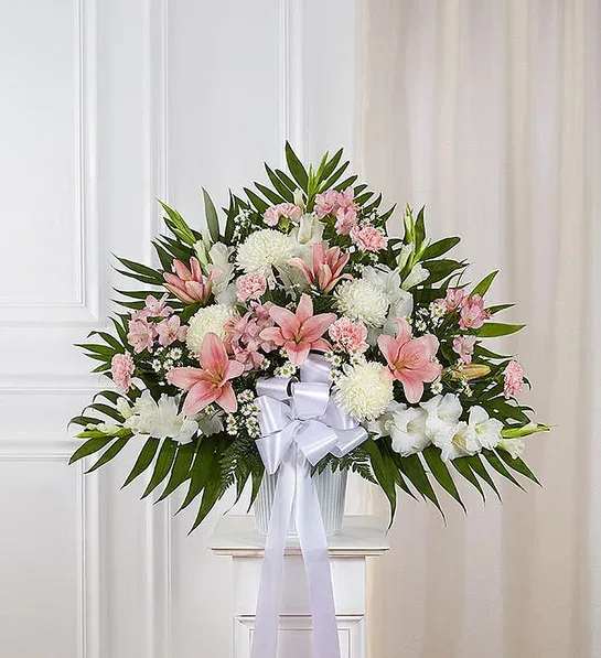Heartfelt Sympathies™ Standing Basket- Pink &amp;White - For those who are grieving, a heartfelt gesture can mean so much. Our elegant pink and white standing basket arrangement will honor the memory of a loved one in a beautiful way. Artistically designed with a medley of pink blooms, this touching expression offers comfort and support when it’s needed most.  One-sided standing basket arrangement with pink roses, Asiatic lilies, Peruvian lilies (alstroemeria) and carnations, white gladiola, football mums and monte casino; accented with assorted greenery and white bow. Large arrangement measures approximately 38&quot;H x 38&quot;W without stand Medium arrangement measures approximately 32&quot;H x 36&quot;W without stand Small arrangement measures approximately 30&quot;H x 34&quot;W without stand Appropriate for the funeral home Wire stand is based on local availability Our florists hand-design each arrangement, so colors and varieties may vary due to local availability