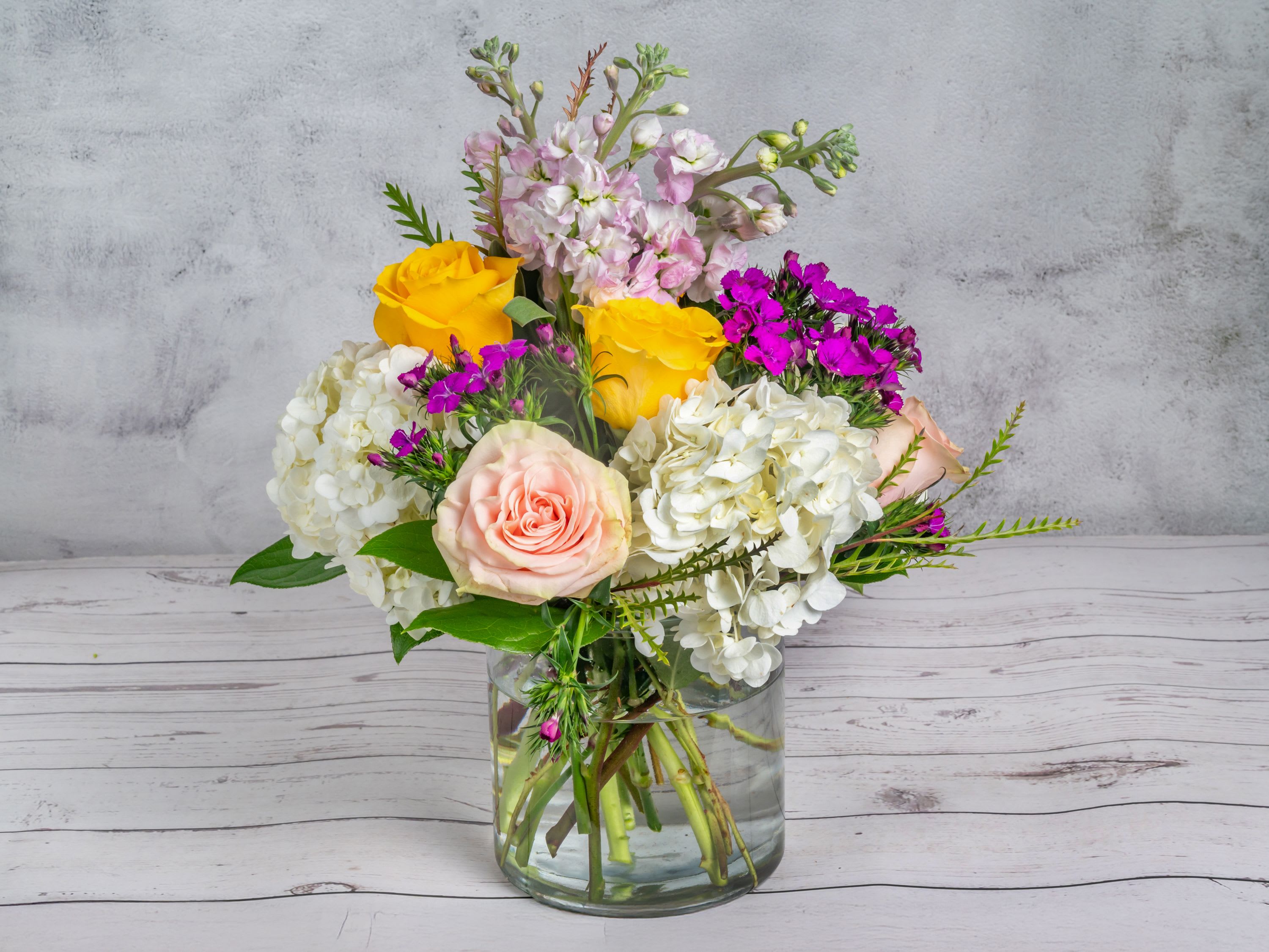 Just For You Just For You - Introducing our "Just For You" Flower Arrangement – a perfect blend of elegance and charm to make any moment memorable. This carefully crafted bouquet features a harmonious mix of lush white hydrangeas, soft blush roses, and bright yellow roses that bring warmth and joy. Accents of delicate pink stock and vivid purple blooms add an enchanting pop of color, while fresh greenery enhances the natural beauty of the arrangement. Housed in a sleek glass vase, this arrangement is ideal for expressing love, gratitude, or celebrating special occasions. Each bloom is thoughtfully selected for its freshness and quality, ensuring that your gesture leaves a lasting impression. Bring a touch of floral luxury to your space or surprise a loved one with a gift that speaks from the heart.