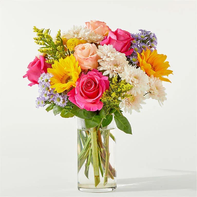 In Good Spirits Bouquet - A colorful blend of roses, sunflowers, and poms to celebrate life events, cheer someone up, or simply make your day brighter. Details Includes approximately 20 stems of florals and greens, as well as a clear glass vase. This bouquet comes with floral food and care instructions, packed carefully within a gift box. As soon as you take your bouquet out of the box, trim the stems at an angle and place them in room temperature water with flower food. For long-lasting blooms, replace water daily and continue to trim stems.
