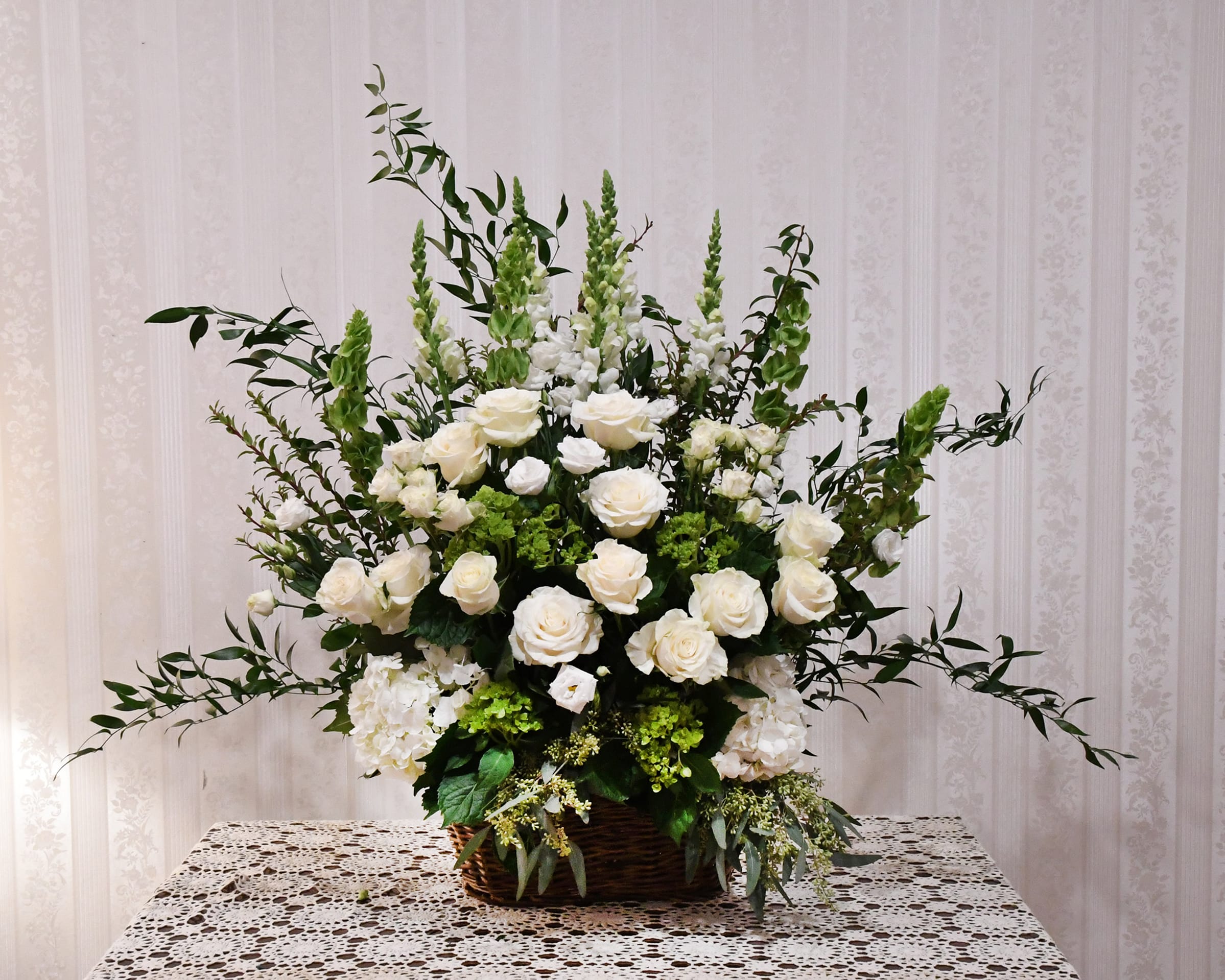 Elegant White Sympathy Basket - A beautiful tribute of classic white blooms.  Elegant roses, hydrangeas, snapdragons and other tasteful blooms.  Arranged in a traditional funeral basket.