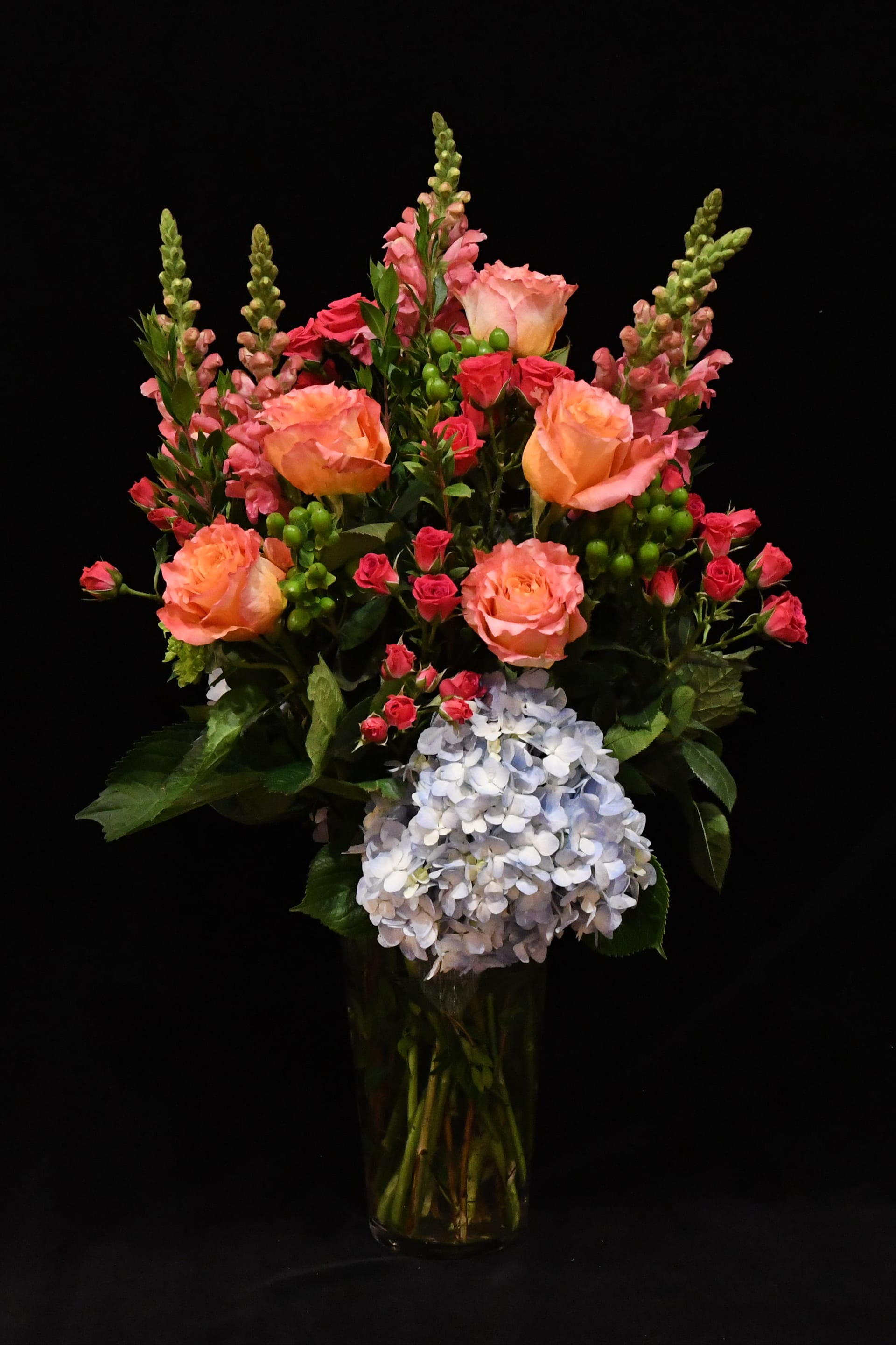 Free Spirit Vase - A gorgeous collection of vibrant color.  Bright roses, snapdragon, spray roses and hydrangea.  Designed beautifully in a tall glass vase.