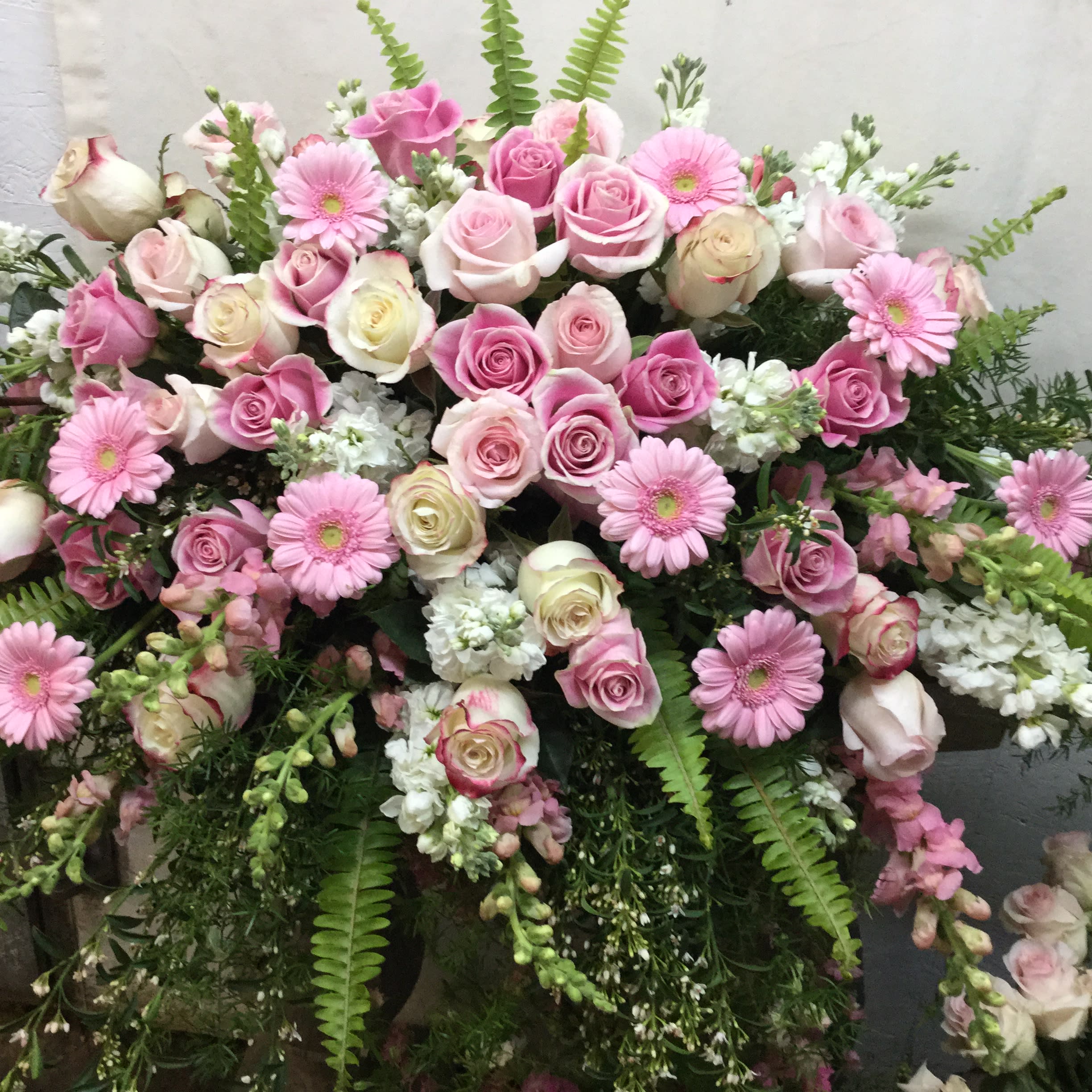 Feminine Pinks Feminine Pinks - A lush casket spray designed with gorgeous seasonal pinks, whites and greens. Includes roses, snapdragon, gerbera daisies and other seasonal favorites
