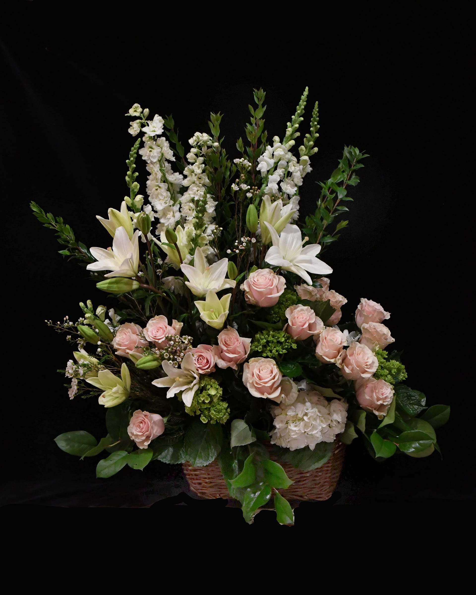 Soft Pink Sympathy Basket - A beautiful tribute of classic pastel blooms.  Elegant roses, hydrangeas, snapdragons and other tasteful flowers.  Arranged in a traditional funeral basket.