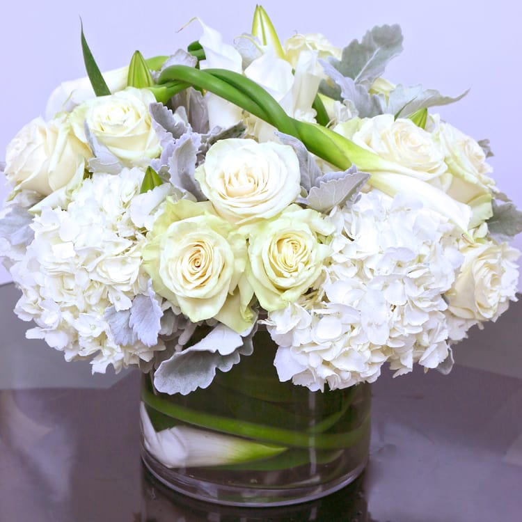 White Garden Mix - An elegant mix of white premium flowers artfully arranged in a clear glass cylinder vase.