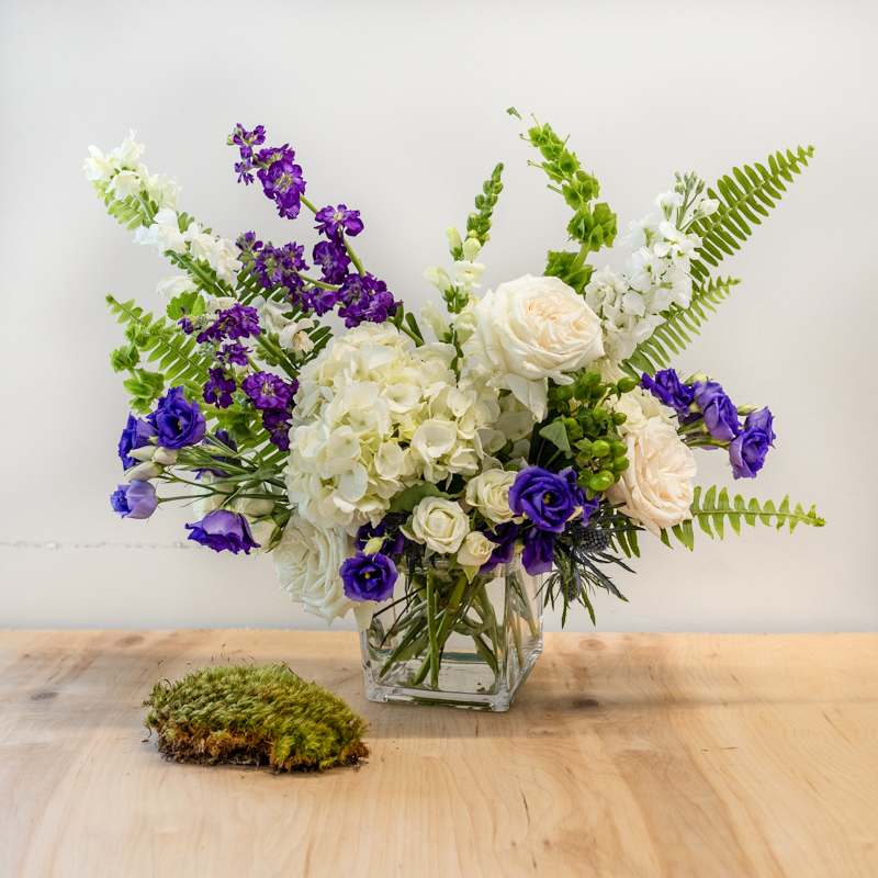 Delight Delight - The perfect surprise. Mixing Hydrangea, Roses, Tulips, and Lisianthus, into a fairly tight arrangement. Perfect for a desk, bedside, or coffee table. Generally 2 colors; white and purple OR white and pink. Approximately 14" X 14" - Shown in DELUXE price point