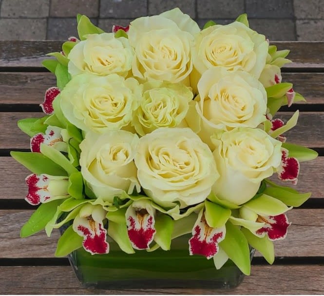 Bespoke Centerpiece Bespoke Centerpiece - This low profile design is placed in a ti leaf wrapped 6"×6" glass cube, and features cymbidium orchids and roses. If desired, request a different color combination in the comments.