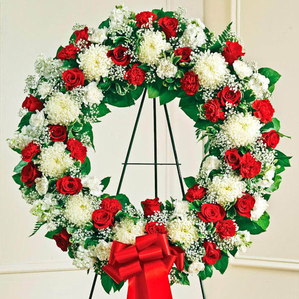 Red and White Standing Wreath - During times of sorrow and loss, a beautiful expression of your sympathies can help convey your comfort and support to family and friends. This lovely standing wreath, crafted by our expert designers using a gathering of fresh, colorful flowers, helps let them know that brighter days are ahead. Created on either an 18 or 24 inch Oasis Wreath form. Flower choices are subject to availability.