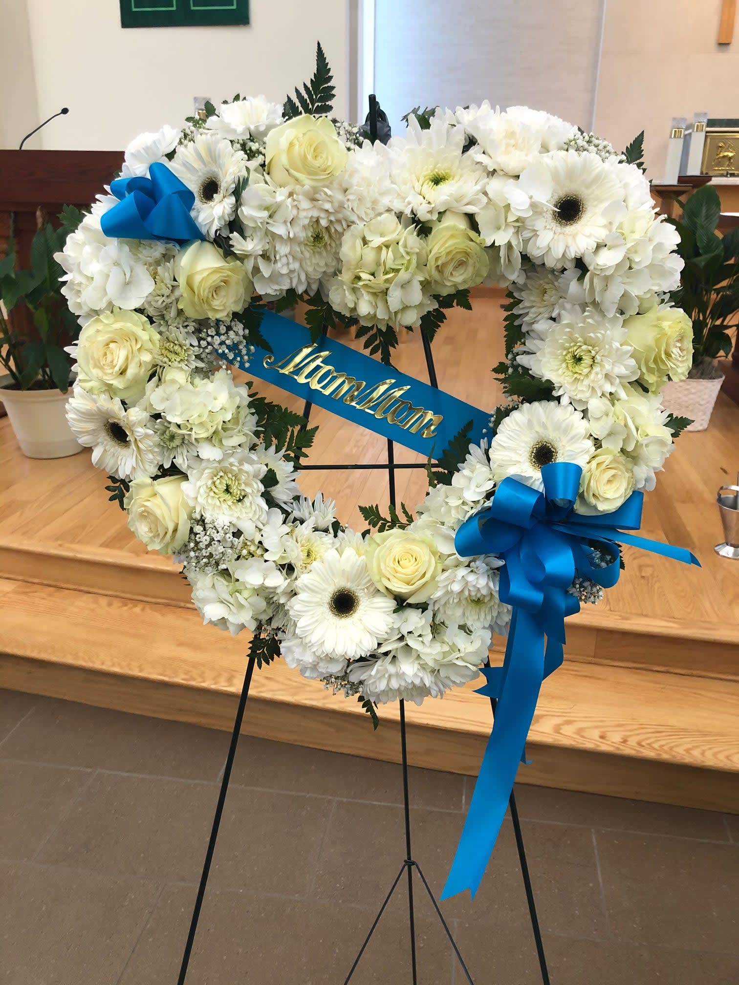 White Open Heart w/ Colored Bow - This tribute shows just how much of your heart is missing now that the person is no longer with us. This Open Heart is made on an 18 inch form. You pick the colors. the flowers selection is at the discretion of the florist. Does not include the banner