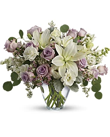 Lovely Luxe Bouquet - Luxe in love! Pale lavender roses, creamy white lilies and delicate greens create a soft, romantic bouquet that's as tender as your feelings. Lavender roses, white asiatic lilies, white lisianthus, white stock, lavender waxflower, and white sinuata statice are accented with dusty miller, seeded eucalyptus, and silver dollar eucalyptus. Delivered in a serenity vase. Orientation: All-Around