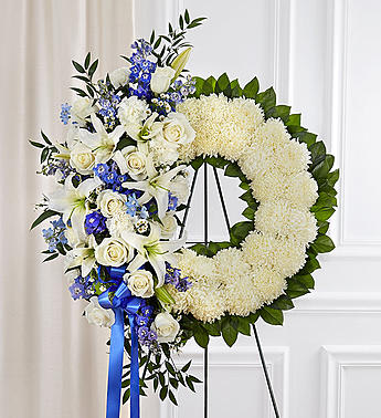 Serene Blessings Standing Wreath- Blue &amp; White - Helping someone find peace after the loss of a loved one can be difficult. If you want to offer your condolences through flowers, our timeless standing wreath in blue and white is a beautiful choice. Artistically handcrafted by our expert local florists with a mix of crisp white blooms and blue delphinium for a lush, full presentation, this grand tribute helps you express all the love and support you have in your heart.  Standing wreath arrangement with blue delphinium; white roses, lilies, football mums, carnations, and monte casino; accented with soft lush greenery Arrangement measures approximately 68 &quot;H x 33&quot;L with easel Appropriate for the funeral home Easel may not be available in all areas Our florists hand-design each arrangement, so colors and assortment may vary based on local availability