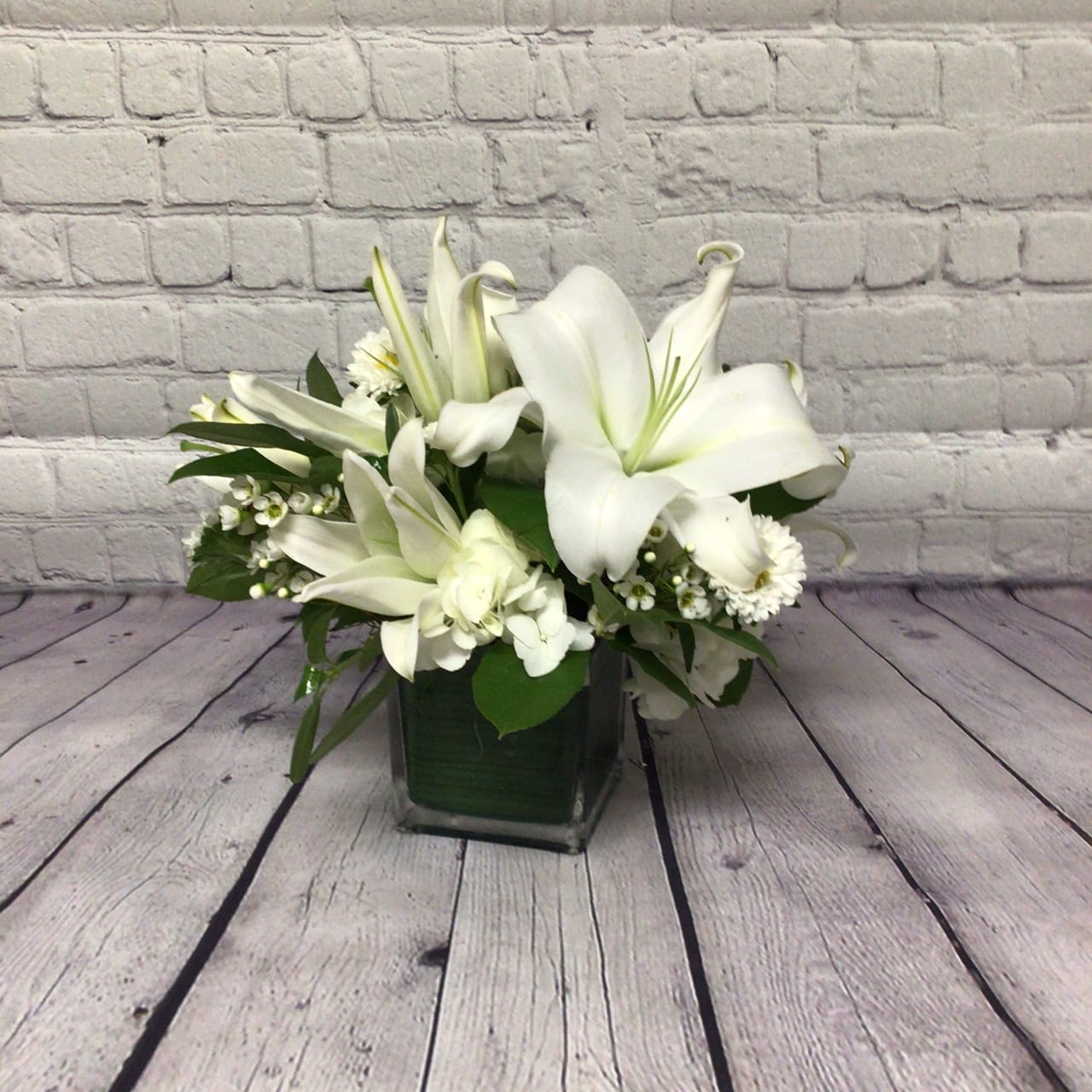 CHARLESTON IN THE GREEN - THIS CLASSIC ALL-WHITE ARRANGEMENT CONTAINS ELEGANT LILIES AND ROSES IN A LEAF-LINED CUBE.   IT'S PERFECT FOR ANY OCCASION OR DECOR.
