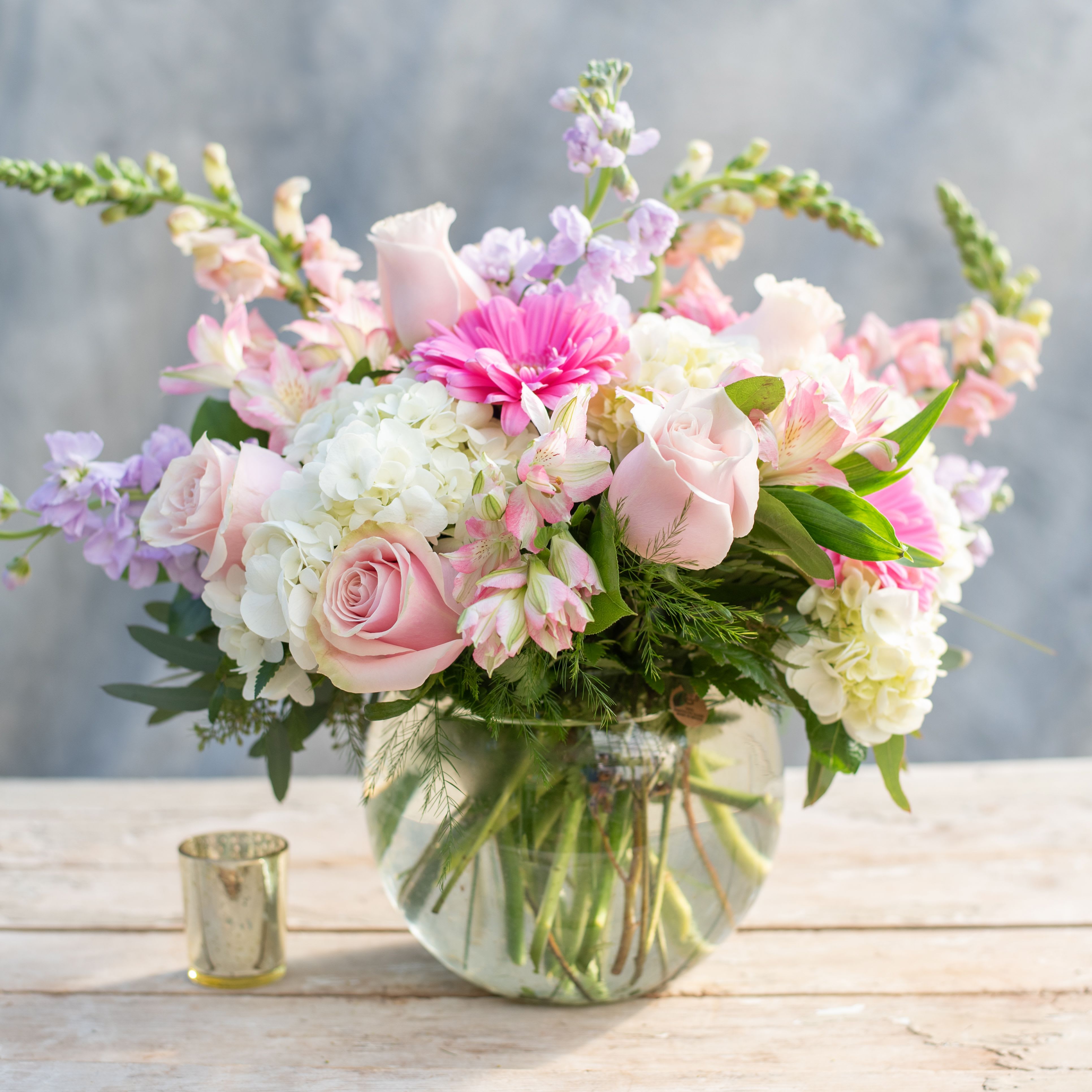 Enchanted - Let this &quot;Enchanted&quot; arrangement fill the recipient with delight. It starts with an 8&quot; bubble bowl spilling over with light pink roses, snapdragons, alstroemeria, whit hydrangea, lavender stock, hot pink gerbera daisies and more.
