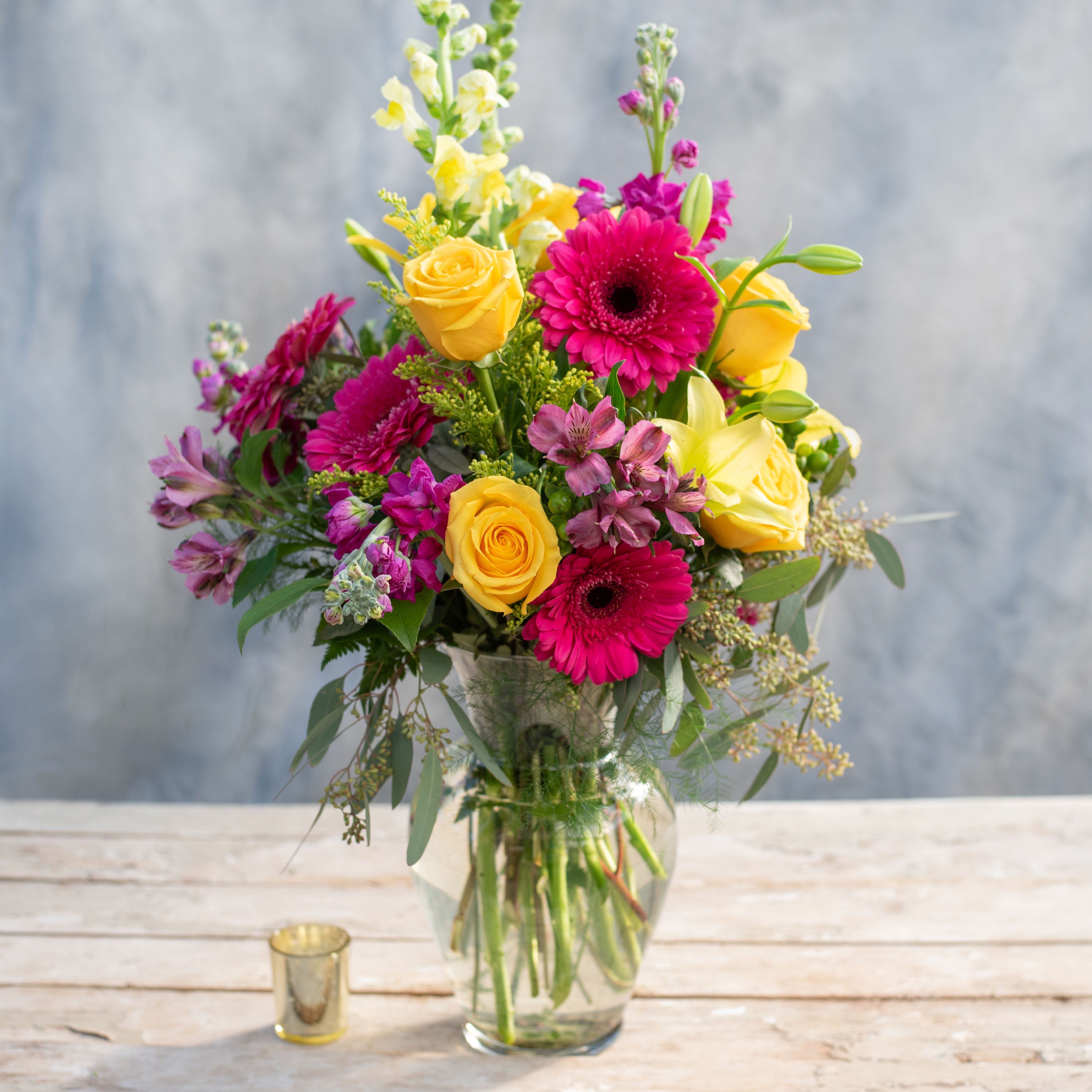 Majestic - All of these vibrant colors together make for one &quot;Majestic&quot; arrangement! Everything from bright yellow lilies and roses to hot pink gerbera daisies and stock to the premium greens in-between.