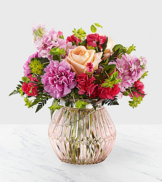 Sweet Spring Bouquet  - From the vivid hot pink and peach roses to the pale pink stock, our Sweet Spring Bouquet is one filled with fresh beauty in each bloom. Set in a ribbed, peach glass vase, an assortment of pink standard carnations, bupleurum and hot pink mini carnations come together with the delights of spring and beautiful texture. This arrangement is perfect for saying, &quot;Feel the warmth of spring,&quot; or &quot;love is in bloom.&quot;  Bouquet is approx. 12&quot;H x 10&quot;W