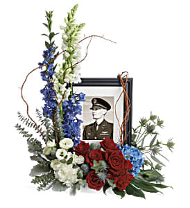 Always With Us Photo Tribute Bouquet - Honor the memory of an always-beloved with this beautiful display bouquet. Designed to surround a favorite photo, its patriotic mix of blue hydrangea with red and white roses is a respectful tribute.  This bouquet features blue hydrangea, red roses, red spray roses, white spray roses, white carnations, blue delphinium, white snapdragons, blue eryngium, dusty miller, curly willow, spiral eucalyptus, parvifolia eucalyptus, aralia leaf and lemon leaf. Arrangement does not include picture frame.   Approximately 22 1/2&quot; W x 25 1/2&quot; H 