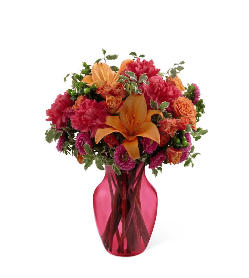 All Is Bright Bouquet - The All Is Bright Bouquet uses bold color to send smiles and cheer across the miles. Orange Asiatic lilies, fuchsia carnations, hot pink matsumoto asters, orange spray roses, green hypericum berries and lush greens are beautifully arranged to create a fantastic bouquet presented in a deep pink glass vase set to brighten your special recipient's day with each vibrant bloom. 