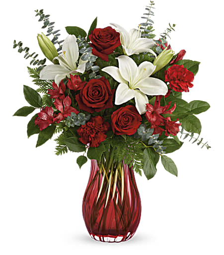 Love Conquers All Bouquet  - Give Valentine’s Day a dramatic twist with this romantic, swirling glass vase. Its ruby red ombre hue is the perfect complement for ravishing red roses and snow white lilies. Red roses, white asiatic lilies, red alstroemeria and red carnations are arranged with spiral eucalyptus, leatherleaf fern and lemon leaf.  Approximately 21″ W x 22″ H.  SUBSTITUTION POLICY – Always deliver the freshest flowers! Please note the bouquet pictured reflects our original design.  If the exact flowers or container in this arrangement are not available, we will create a beautiful bouquet with the freshest available flowers.