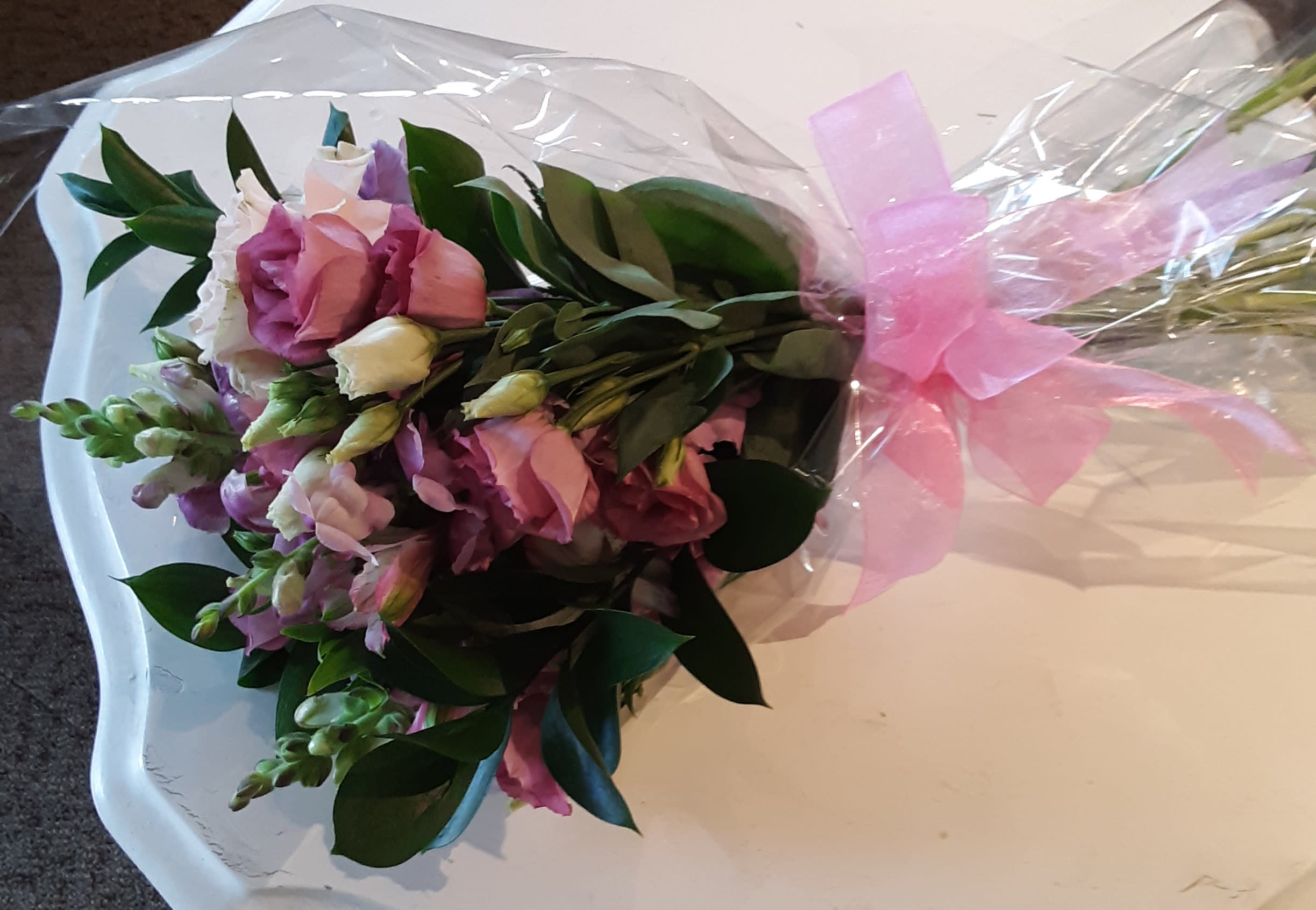 "Queen for a Day" Bouquet "Queen for a Day" Bouquet - Perfect for gifting on birthdays, Anniversaries, Mother's Day, Valentine's Day, or any day of the year! This bouquet will be delivered in the style pictured, but flower choice by Designer will be based on seasonality and availability. A twist on the classic boxed arrangement, the cellophane wrap and bow accent the flowers and display them in all their grand glory. Bouquet also includes 1 wrapped solid milk chocolate rose for the recipient's sweet tooth!