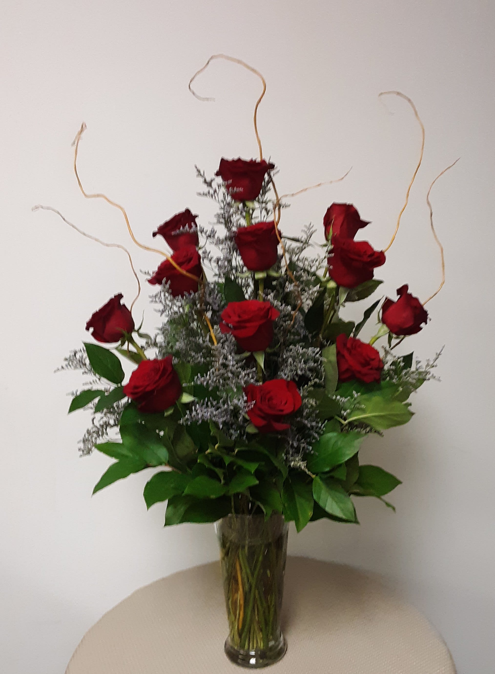Endless Love Rose Arrangement Endless Love Rose Arrangement - One dozen incredible long-stemmed PREMIUM roses, the finest quality greenery, curly willow branches, and a saucy pop of the accent color of limonium, all artfully arranged in a beautiful clear glass vase. Truly the finest and most exquisite rose bouquet in the area!! Available in 4 amazing color palettes: true red, pink, bright yellow or lavender with fuchsia edges. (Approximately 18 inches wide x 32 inches high) Specify your color choice in the Special Instructions section when ordering. If no color choice is indicated RED will be delivered.