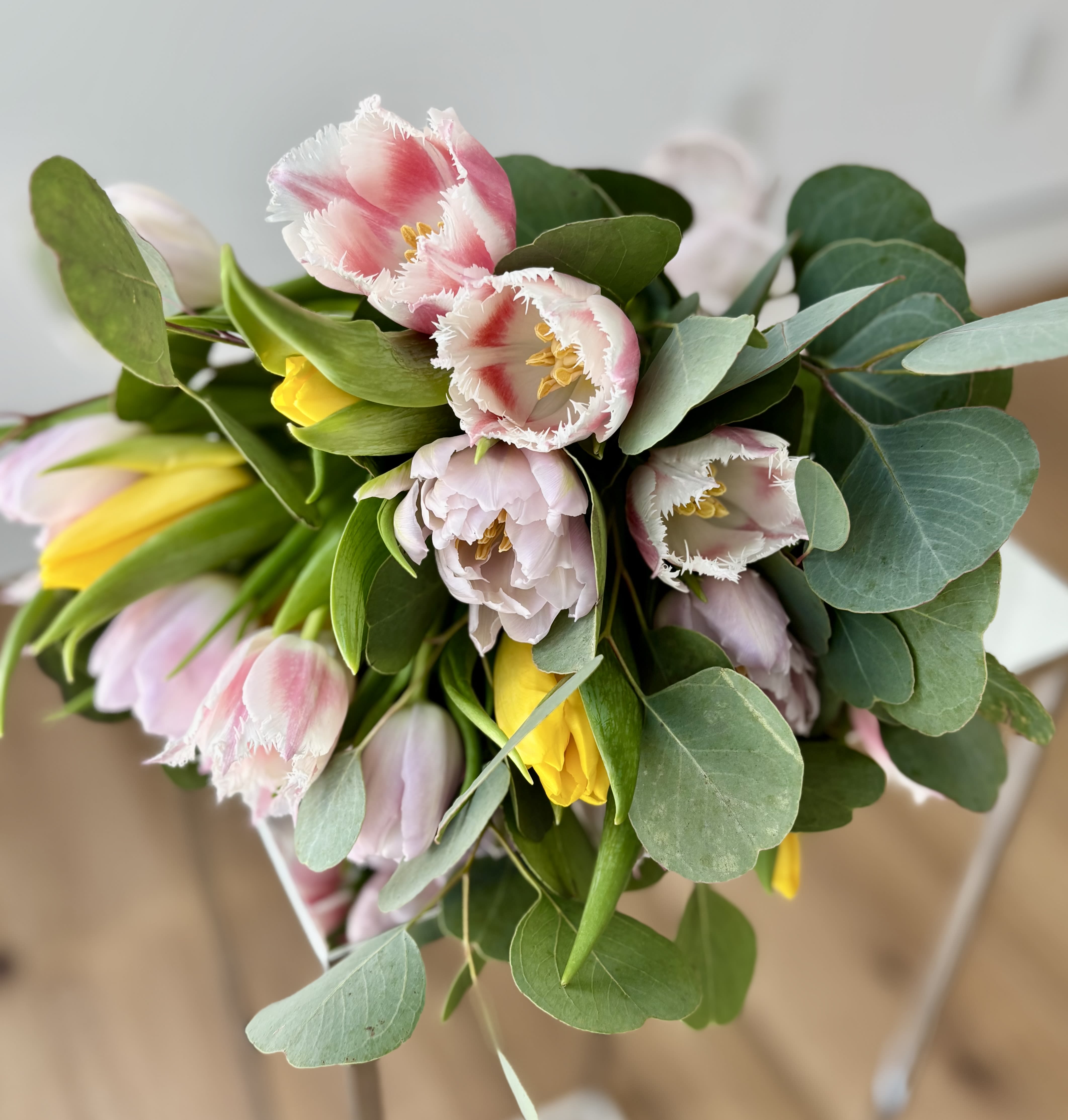 Bouquet of Tulips - A bouquet of 25 premium tulips with greenery (no vase included), hand-tied with ribbon. A mix of different varieties (frilly tulips, double peony tulips, parrot tulips, ....) and colors to make a lovely spring arrangement in your own vase. Just recut the stems and pop them into the vase. The colors and variety of tulips may vary depending on the availability.