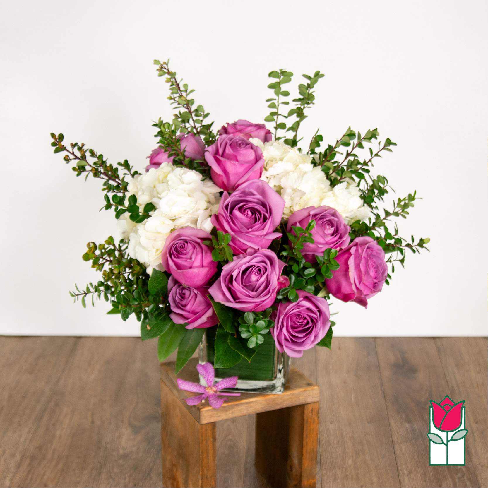 Beretania's Compact Bouquet (Lavender Rose) [Lavender Hue Varies] - Elevate your space with the Beretania Florist Compact Bouquet, a charming floral arrangement that effortlessly combines elegance and versatility. Housed in a beautiful 4&quot; glass cube vase, this compact bouquet features a delightful composition of hydrangeas, foliage, and your choice of roses in various colors, allowing you to tailor it to your preferences.  Whether you opt for the timeless allure of red roses, the soft romance of pink, or the vibrant cheerfulness of yellow, each variant of the compact bouquet brings a unique charm to any setting. The meticulous design ensures a harmonious blend of textures and hues, creating a visually appealing arrangement that suits any occasion.  For those seeking an extra touch of sophistication, consider our upgraded option – the Olivia Compact Bouquet. This variant remains true to the original design but introduces the exotic beauty of colorful cymbidium orchid blossoms, elevating the bouquet to a new level of elegance.  Perfect as a thoughtful gift or a stunning addition to your own space, the Beretania Florist Compact and Olivia Bouquets are crafted with precision and care, promising a burst of floral beauty that suits your style and preferences. Choose the color that speaks to you and let the timeless beauty of these bouquets brighten your day.